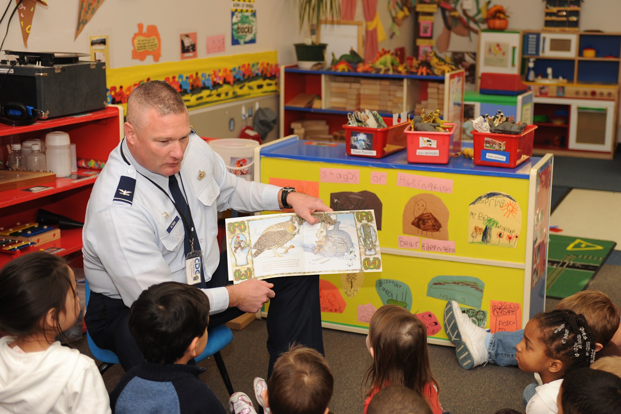 LANGLEY AIR FORCE BASE, Va. – Col. Kevin Altman, 1st Mission Support Group commander, reads “The Mitten” to children at the child development center Dec 8. The book club gives community volunteers and the mayor an opportunity to visit preschool classrooms each month to promote a healthy habit and affection for reading.  (U.S. Air Force photo/Airman 1st Class Gul Crockett)

