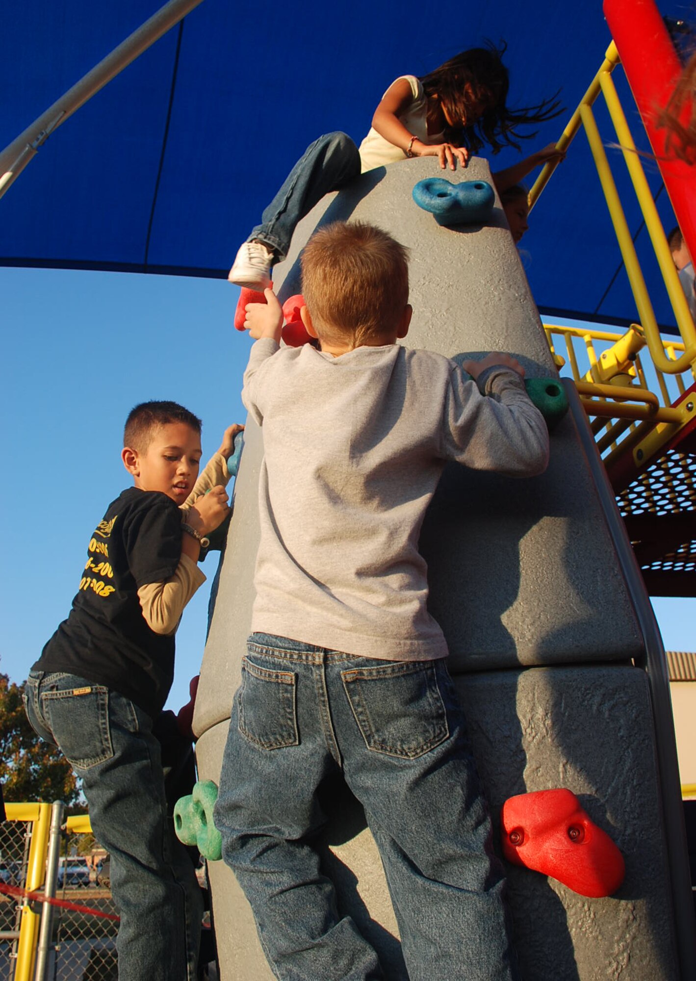 LAUGHLIN AIR FORCE BASE, Texas –Children from the Youth Center here play on the rock climbing part of the  new playground set here for the Youth Center Dec. 8. “The new playground has been long awaited,” said Kristin Tighe, Youth Center director. “The old playground was very outdated, but this one has all new equipment including rock and wall climbing. It’s a playground geared toward physical fitness and older children.” (U.S. Air Force photo by Airman 1st Class Sara Csurilla)