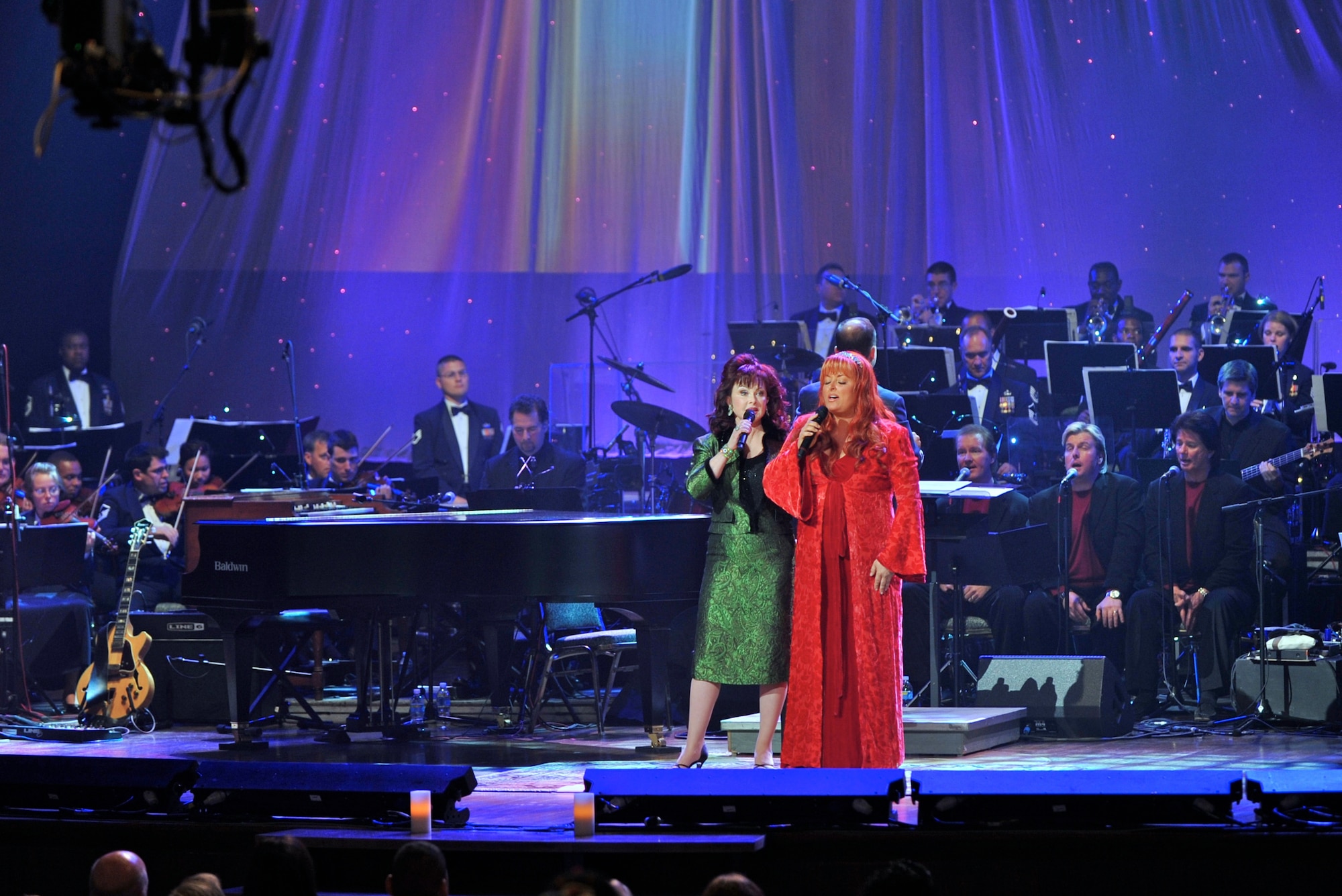 Country music artists Wynonna and Naomi Judd sing classic holiday music while the Band of the Air Force Reserve and Air Force Strings perform in the background during the 2008 Holiday Notes from Home concert recorded Oct. 6.  The concert is annual holiday event recorded at the Grand Ole Opry House in Nashville, Tenn., as a tribute to military men and women serving around the world.  The show airs on Great American Country throughout December and also on American Forces Network channels for service members and their families stationed overseas.  (U.S. Air Force photo/Ken Hackman)