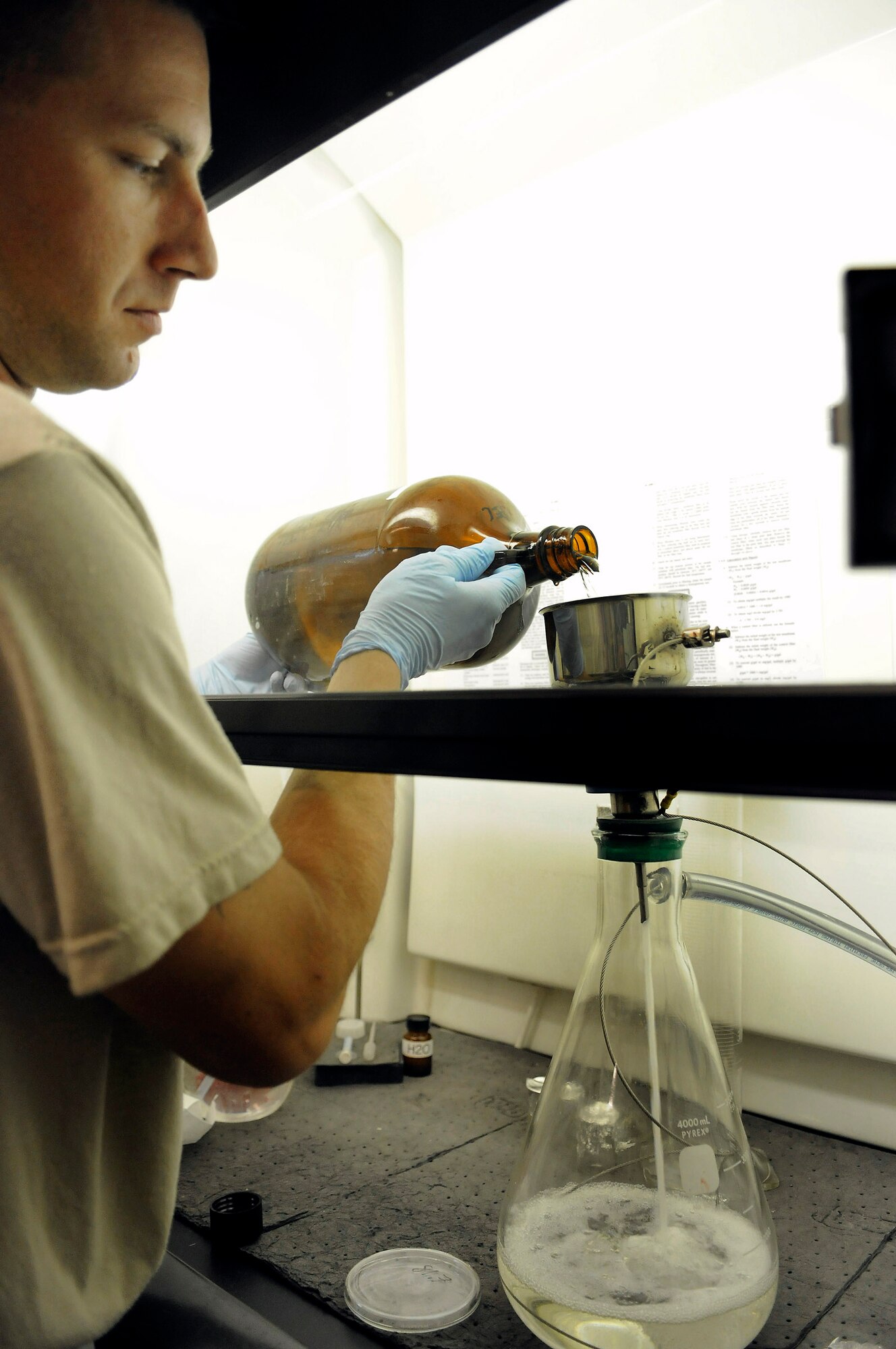 Staff Sgt. Ronald Gasper pours fuel through a filter membrane into a beaker as part of a bottle method test Dec. 8 at an air base in Southwest Asia. The filter membrane is weighed before and after a bottle method test; the differences in weight will show the amount of impurities in the fuel. The weekly bottle method test is used to test the fuel truck's filter separator and how well it is screening impurities from the fuel. Sergeant Gasper is a fuels lab technician assigned to the 379th Expeditionary Logistics Readiness Squadron and deployed from Scott Air Force Base, Ill. He is a native of Omaha, Neb. (U.S. Air Force photo/Tech. Sgt. Michael Boquette) 
