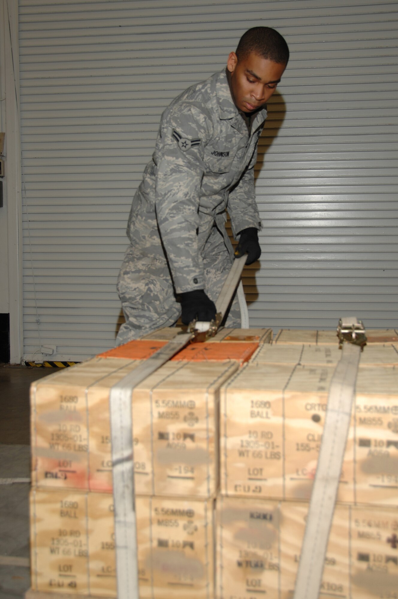 Airman 1st Class Kyle Johnson, a munitions specialist with the 88th Operations Support Squadron, ties down boxes of small arms ammo to a pallet in preparation for shipment Dec. 5. at the Wright-Patterson Air Force Base weapons storage area. Johnson, who hails from Columbus, Ohio, participated in a base crisis response exercise which simulated the deployment of more than 200 personnel and nearly 60 tons of cargo to an air base in Asia. (U.S. Air Force photo/Ben Strasser)  