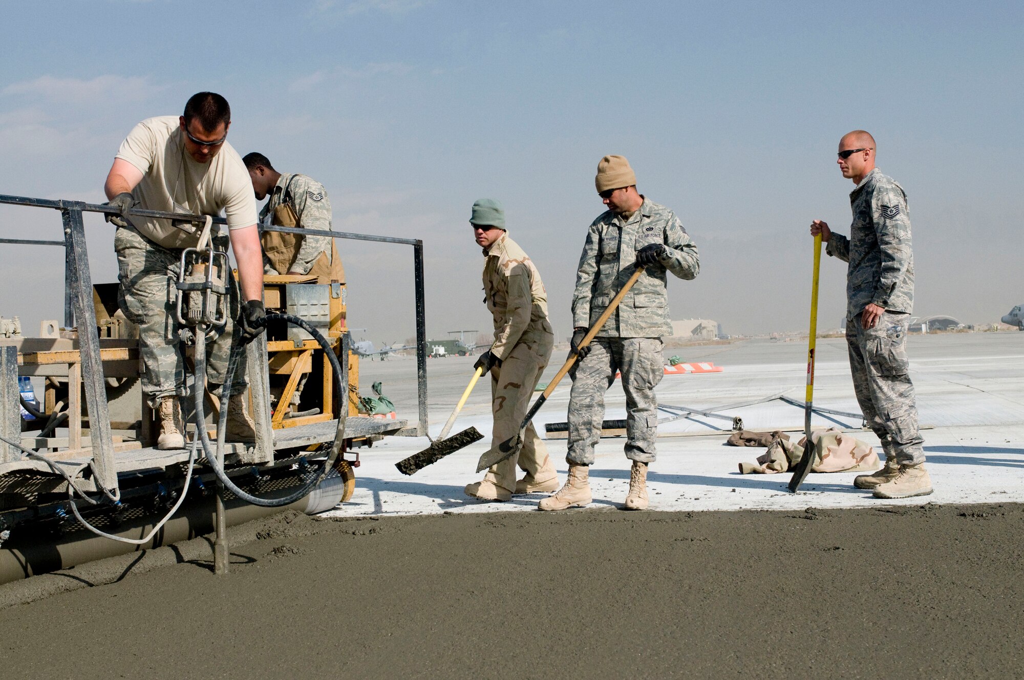 Airmen of the 455th Expeditionary Civil Engineer Squadron lay concrete on Thanksgiving Day, Nov. 27., at Bagram Air Field, Afghanistan. Taking advantage of every day possible to lay concrete, the Airmen work hard to expand the flightline before cold weather makes laying the temperamental concrete impossible. (U.S. Air Force photo by Staff Sgt. Samuel Morse)(Released)