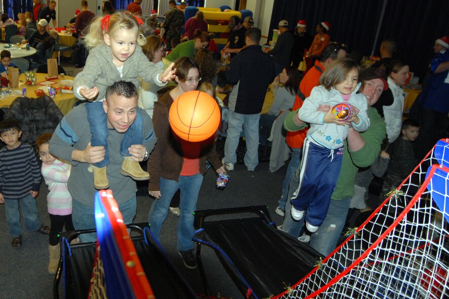 Sitting on her father’s shoulders, Jenna Moening tosses a basketball and hopes to score a prize from the prize basket at the 2008 Wing Children’s Christmas Party at The Landings Club, Dec. 7. Jenna and her father, Tech. Sgt. Seth Moening, 436th Civil Engineer Squadron, were only two of the more than 300 guests who visited the Christmas party. (U.S. Air Force photo by Tech. Sgt. Kevin Wallace)