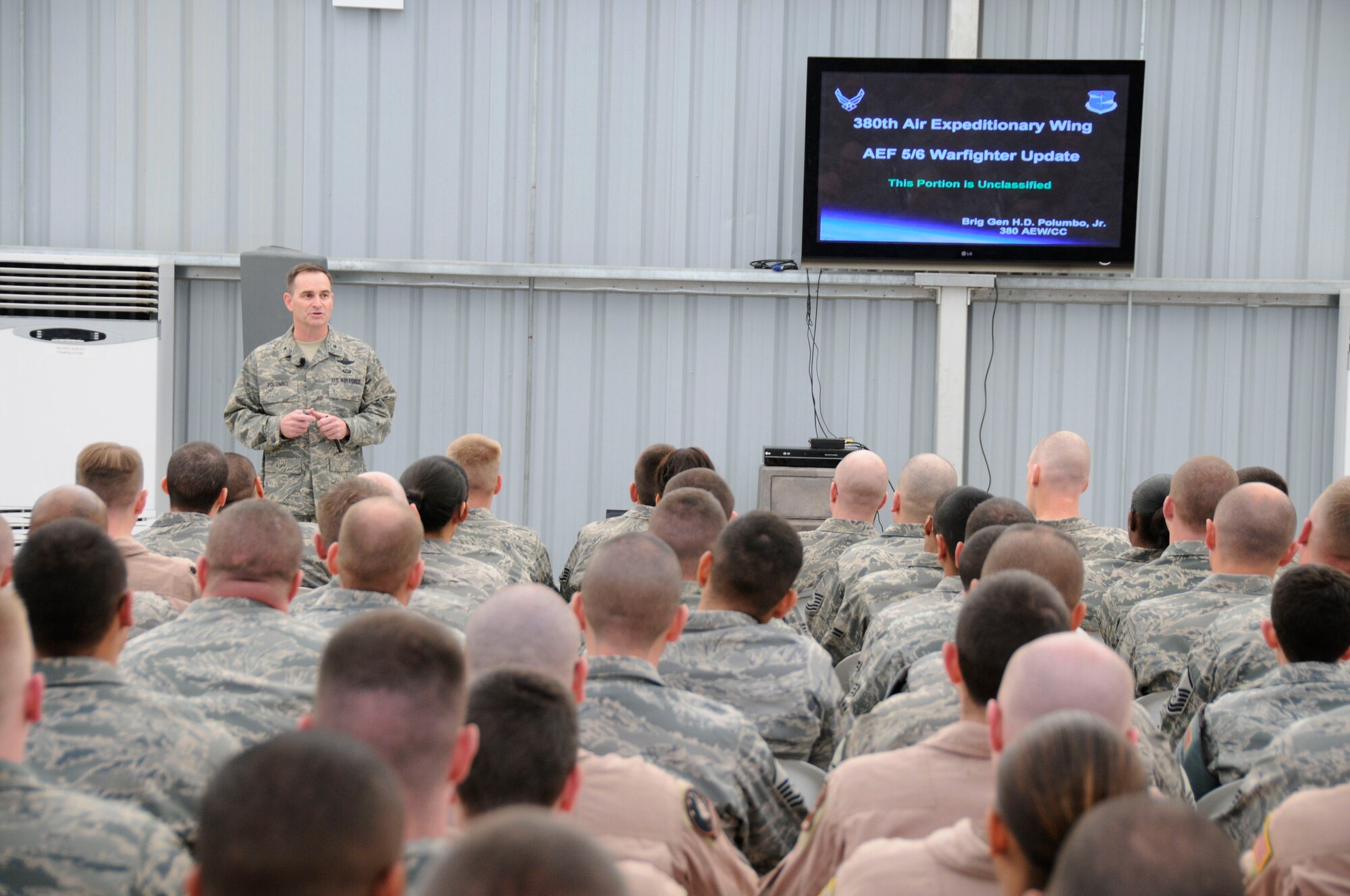 SOUTHWEST ASIA -- The 380th Air Expeditionary Wing Commander, Brig. Gen. H.D. Polumbo, Jr., addresses a crowd of over 400 Airmen during the warfighter briefing here Dec. 10. The commander thanked the Airmen for their service and encouraged them to maintain the successful battle rhythm they've held since their deployment began. The briefing is intended to share highlights from the AEF rotation and remind Airmen to stay focused through the transition.  (US Air Force photo by Tech. Sgt. Christopher Campbell) (released) 