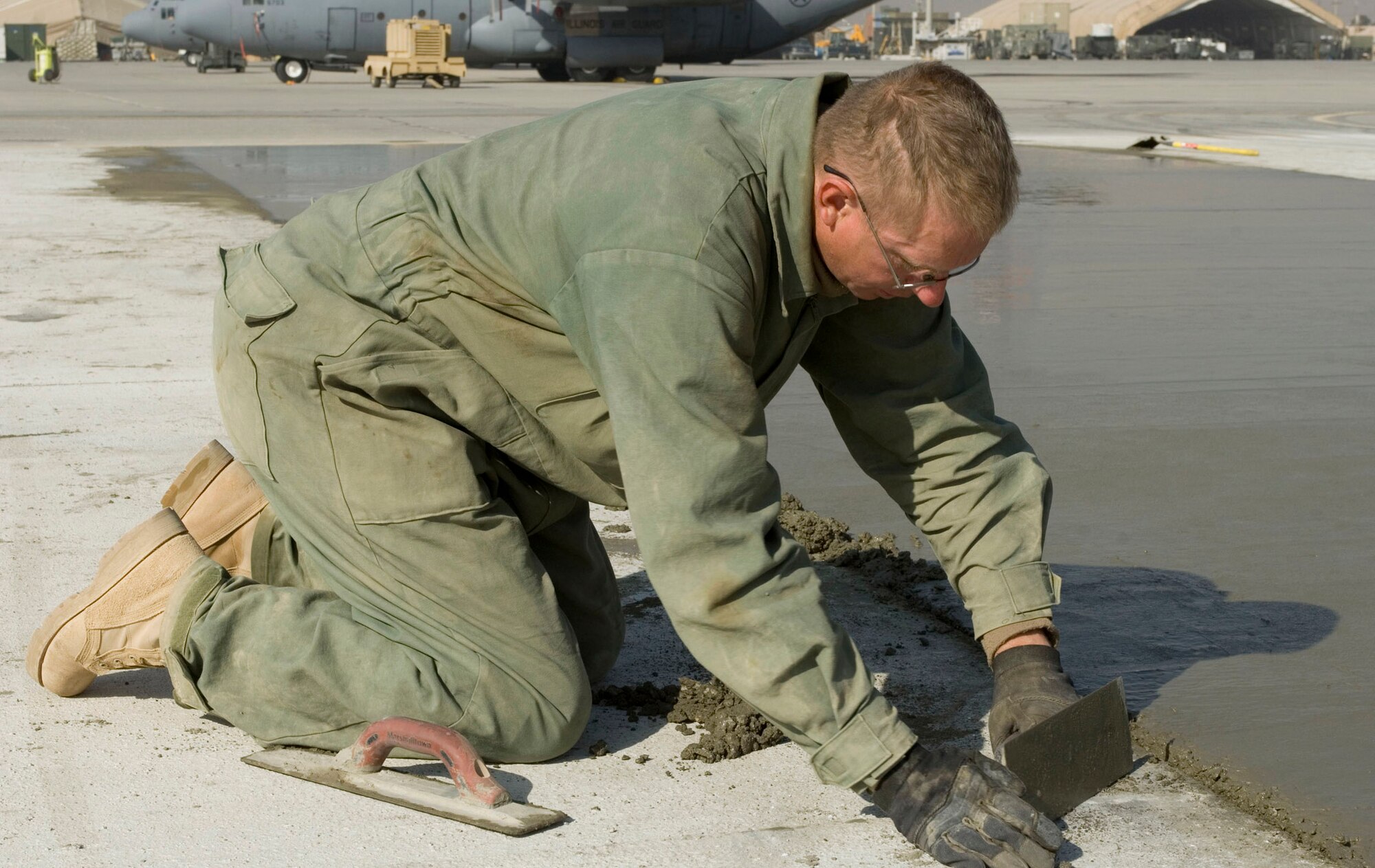 Staff Sgt. Edward Sells, a 455th Expeditionary Civil Engineer Squadron "dirt boy," smoothes freshly poured concrete on the flightline at Bagram Air Field, Afghanistan, Nov. 25. More than 3,500 cubic meters of concrete are being poured this AEF rotation to expand and construct ramps and taxiways as part of airfield expansion projects. Sergeant Sells is deployed from Lackland Air Force Base, Texas. (U.S. Air Force photo by Staff Sgt. Rachel Martinez) (Released) 