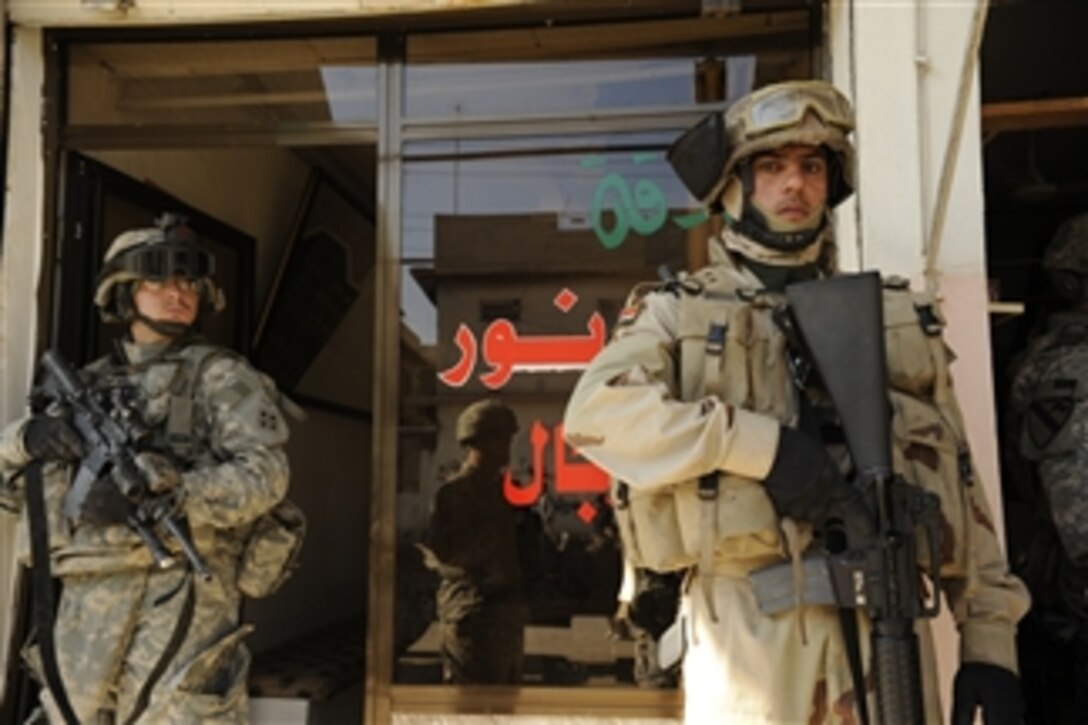 U.S. Army Spc. Robert Huth, 1st Battalion, 8th Infantry Regiment, Fort Carson, Colo., and an Iraqi soldier secure the area while delivering a generator to a locksmith in Karama, a neighborhood in Mosul, Iraq, on Dec. 3, 2008.  