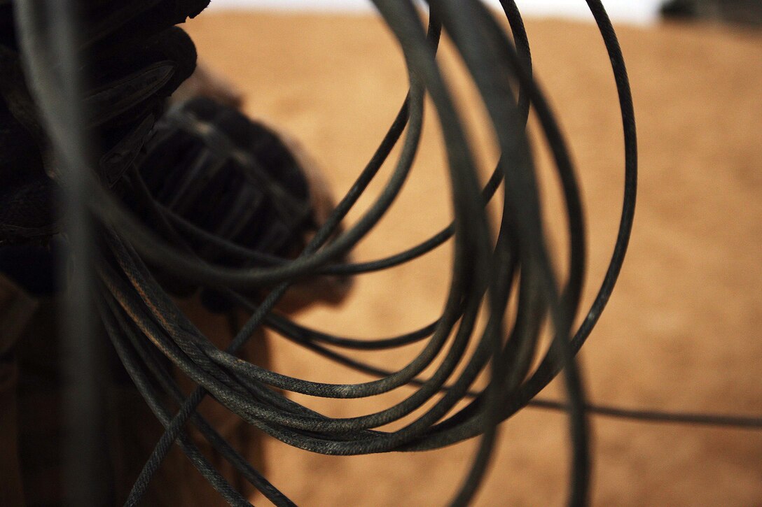 Cpl. Ivan R. Romero, a 22-year-old squad leader with 1st Combat Engineer Battalion, Regimental Combat Team 5, unwinds a spool of detonation cord that will ignite explosives during a training exercise at Combat Outpost Rawah, Iraq, Dec. 17.  The combat engineers, who are supporting Task Force 3rd Battalion, 7th Marine Regiment, RCT-5, discharged four different types of explosives over the course of three detonations.  The explosives included C4, shape charges, platter charges and grape shots â?? a type of field expedient claymore.::r::::n::