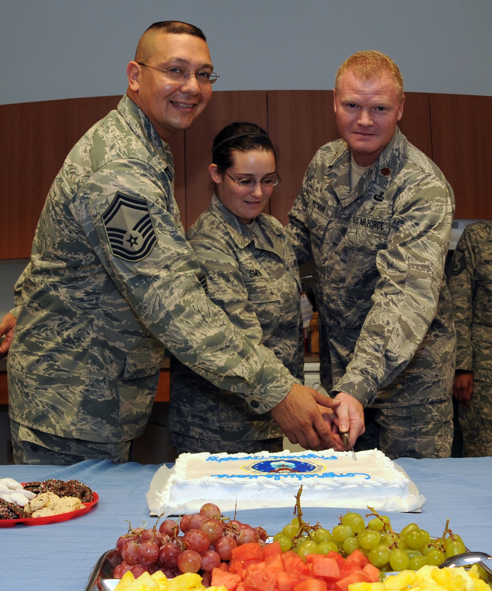 ANDERSEN AIR FORCE BASE, Guam - Senior Master Sgt. Leonardo Castro (left), Staff Sgt. Rebecca Smen (center), and Maj. Bradley Reyman (right), 36th Medical Operations Squadron physical therapy staff, pose while cutting a cake to celebrate the Health and Wellness Center's new physical therapy clinic grand opening Dec. 11.  (U.S. Air Force photo by Senior Airman Jonathan Hart)