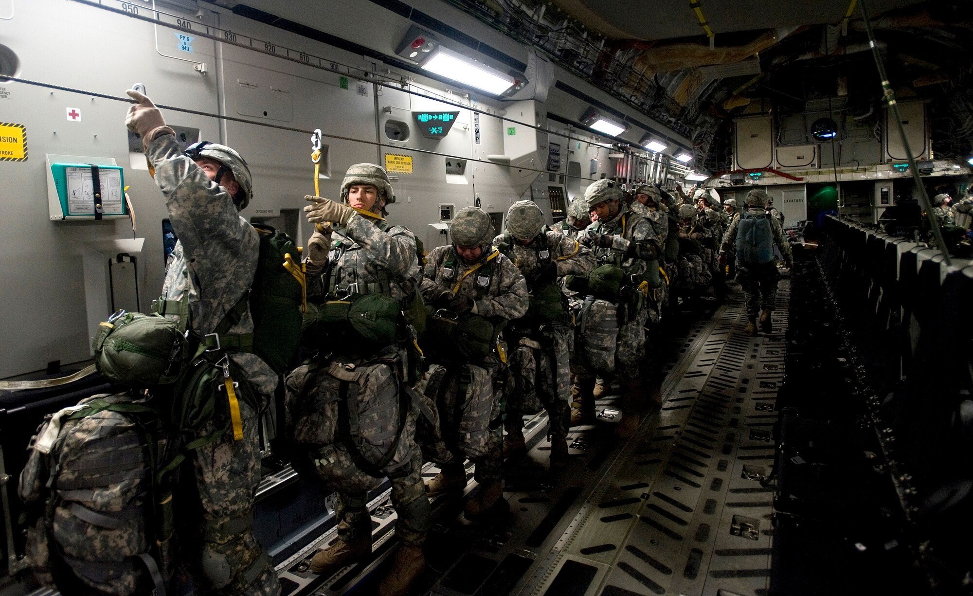 ELMENDORF AIR FORCE BASE, Alaska -- 1-501 Infantry Soldiers hooks themselves on to cable prior to their jump Dec. 10. The 4th Brigade Combat Team, 25th Infantry Division partnered with the 517th Airlift Squadron, Hickam and McCord Air Force Base is using this week practice jumps prior to the deployment. Roughly 1,300 4-25 Soldiers will be jumping out of C-17 Globemaster IIIs during the week. (U.S. Air Force photo by Senior Airman Jonathan Steffen)