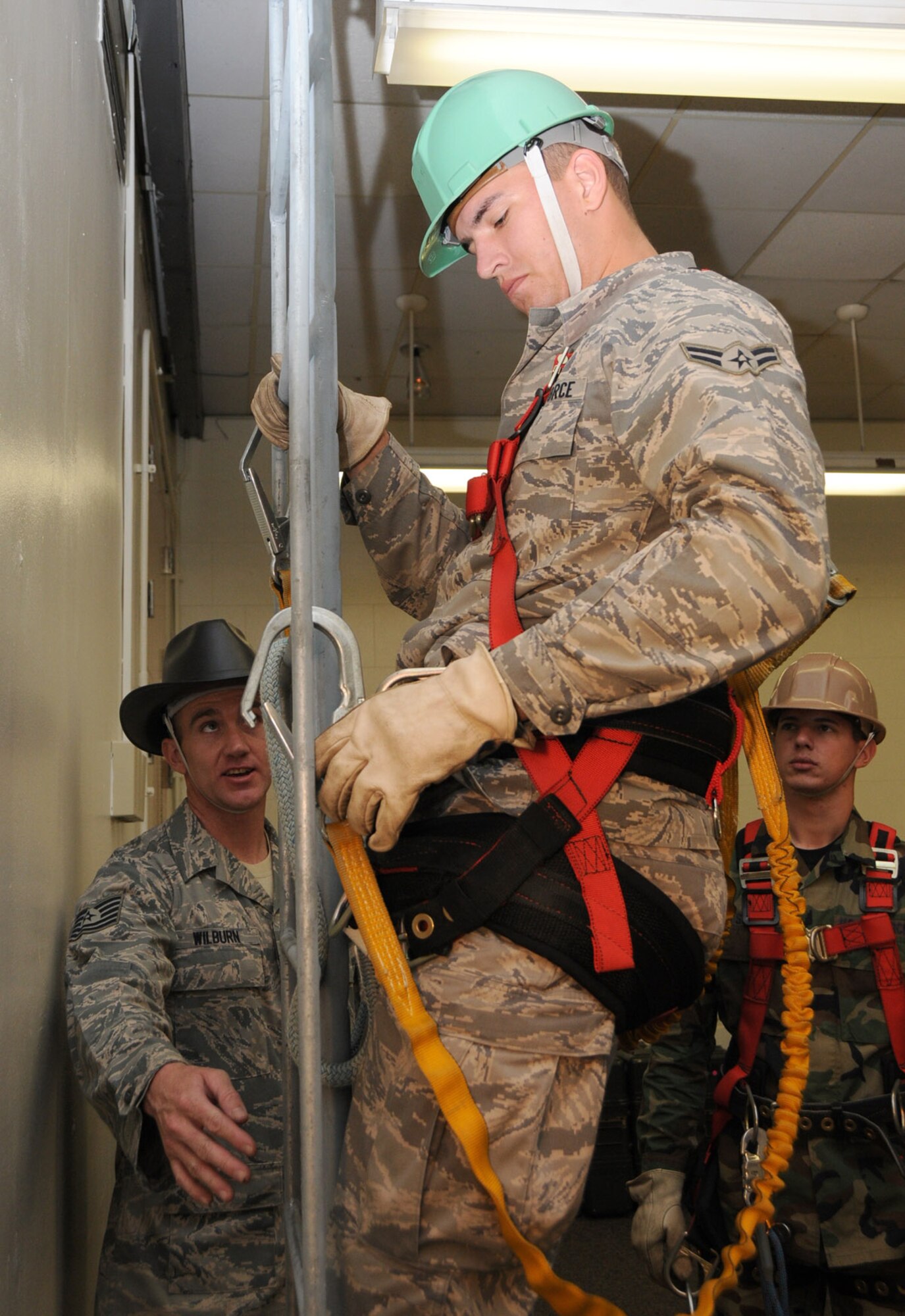 Tech. Sgt. Daniel Wilburn, left, guides one of his students, Airman 1st Class Bryson Parrish, on safety procedures on a classroom ladder  before undertaking a 40-foot climb.  (U.S. Air Force photo by Kemberly Groue)
