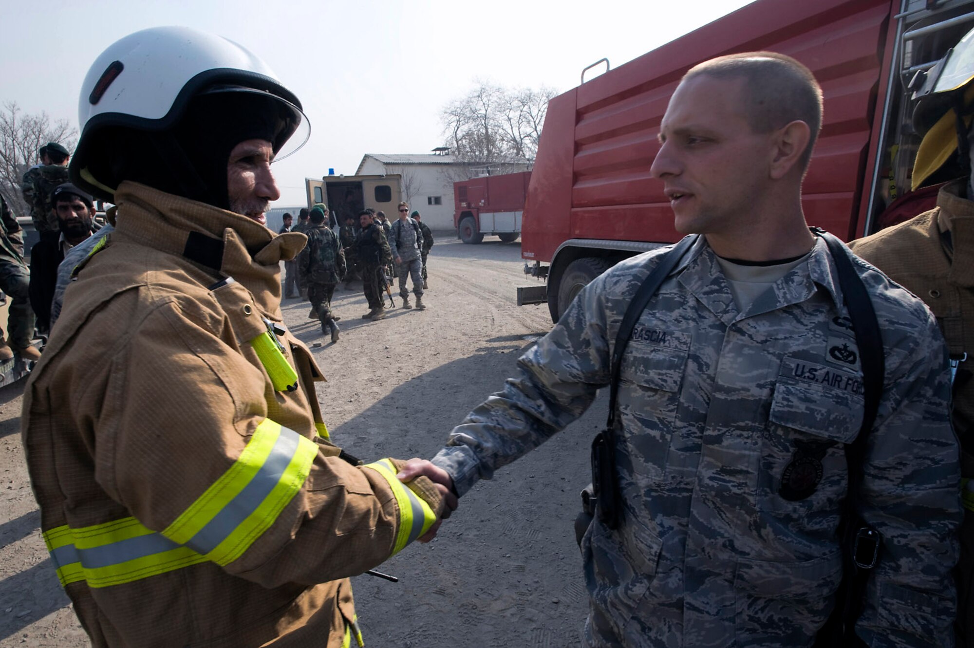 Afghan National Army Air Corps Joint Fire Academy commandant, Master Sgt. Mike Marascia, shakes hand with ANAAC fire chief, Maj. Razuddin after a successful exercise. The ANAAC firefighters extinguished a fire in a abandoned building. Sergeant Marascia is a fire protection mentor. (U.S. Air Force photo/Master Sgt. Keith Brown) 
