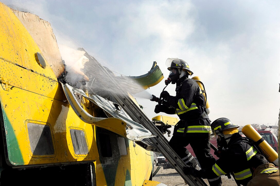 Airmen from the 438th Air Expeditionary Wing douse a fire on a helicopter during an open house at the Afghan Joint Fire Academy. The open house showcased training exercises used at the academy to members of the wing and highlighted progress made by the Afghan firefighters during the past nine months. (U.S. Air Force photo/Master Sgt. Keith Brown)