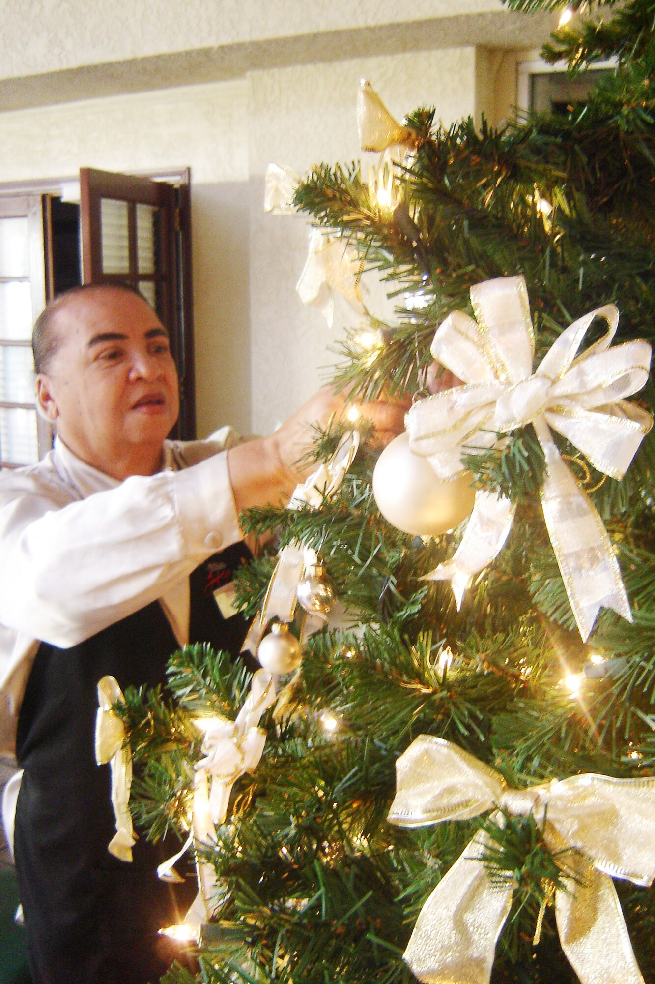 Lizzie Greene, lead food services at the Hap Arnold Club, puts the finishing touches on the Christmas tree in the club’s atrium on Wednesday. Greene said the club will have nine trees. Several local base and community volunteers also decorateds the Hap Arnold House for the holidays. The work of these holiday helpers will set the atmosphere for the wing commander’s holiday reception tonight, and will add to the season’s cheer on Christmas Day when Santa’s assistants will serve turkey dinner to those who will be working on base. (U.S Air Force photo by Will Alexander)