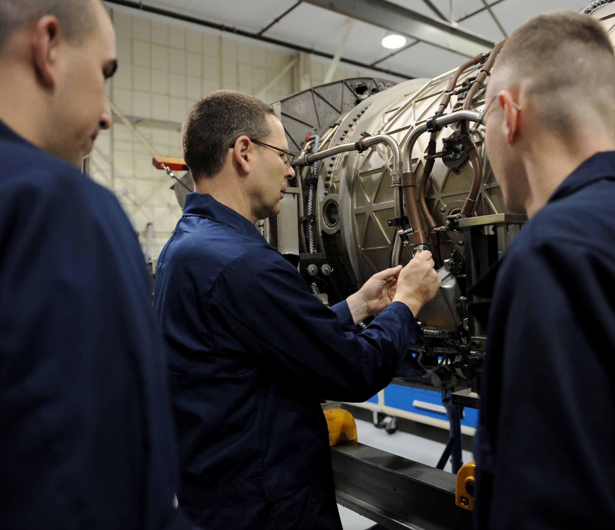 LANGLEY AIR FORCE BASE, Va. --  Chief Master Sgt. Kevin Slater, 1st Fighter Wing command chief, loosens a bolt on the engine of an F-22 at the 1st Component Maintenance Squadron while Airman 1st Class Erin Diaz and Senior Airman Justin Laraby look on Dec. 10. Chief Slater toured the squadron and received a lesson on the engines while getting to know some of the Airmen.  (U.S. Air Force photo/Airman Rebecca Montez)