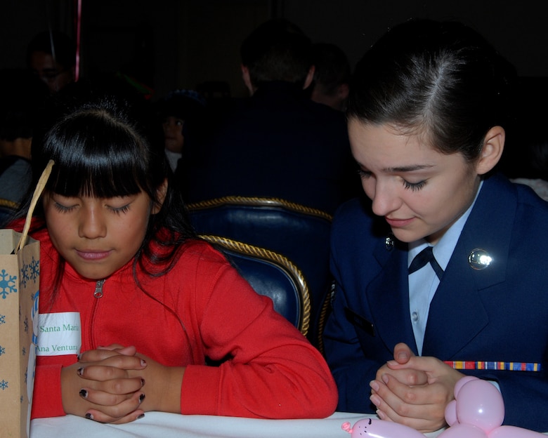 VANDENBERG AIR FORCE BASE Calif. -- Airman 1st Class Dallas Cole prays with 
Ana Ventura from Santa Maria at Operation Kids Christmas held at the Pacific Coast Club. (U.S. Air Force photo/Airman 1st Class Antoinette Lyons)
