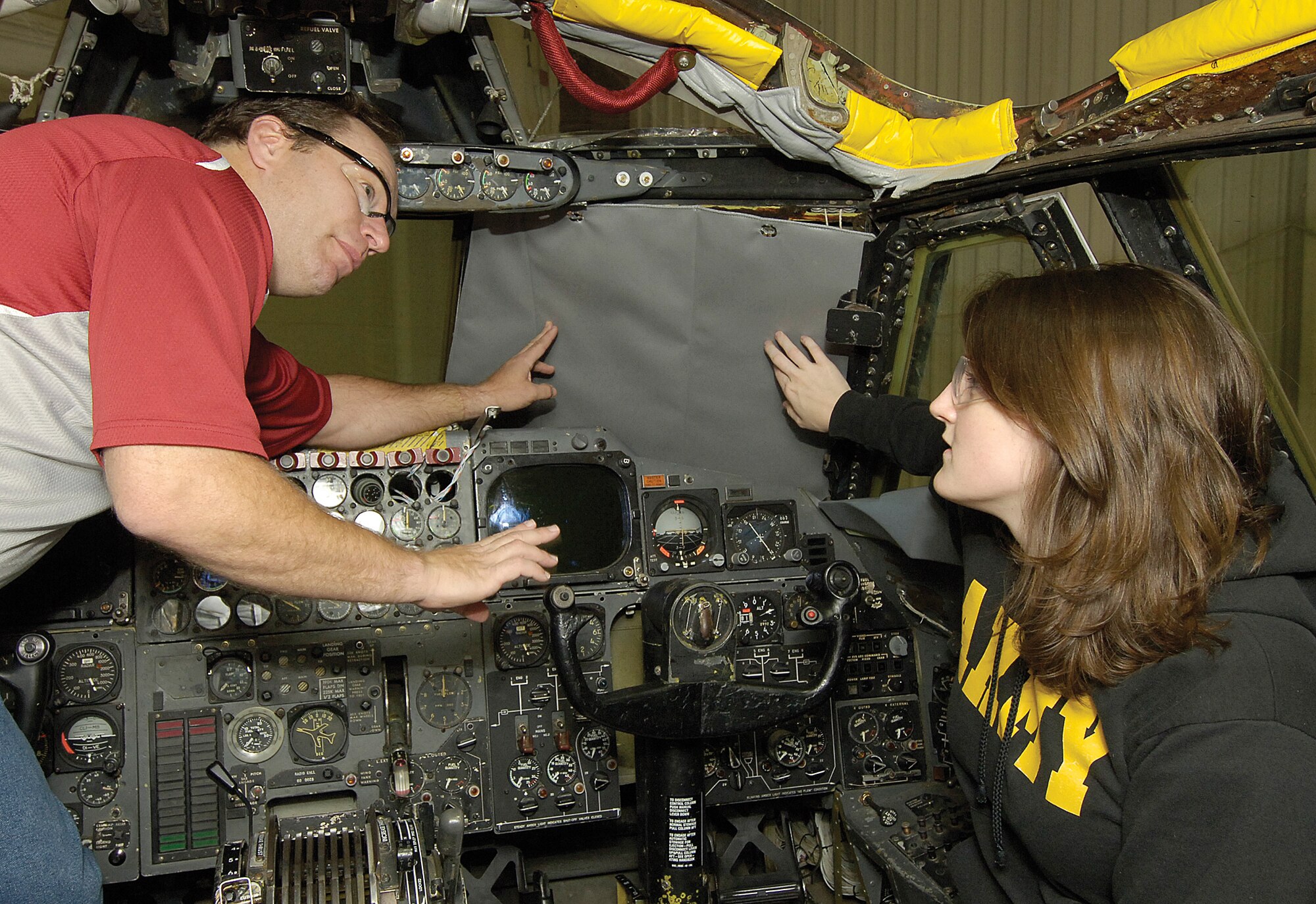 Tinker B-52 engineer Matthew Yost and engineering intern Jennifer Hoffman discuss a prototype B-52 thermal curtain they hold in front of a cockpit window.  The fitted, rigid curtains will be created for each window and sewn in the fabric shop of Bldg.. 229.  After suggestions from Barksdale Air Force Base, La. B-52 crews, the curtains should be ready for manufacturing, according to Mr. Yost.  Reflective on the outside, rubberized on the inside, the curtains would protect the crew from the blinding light of nuclear arms.  Current shades are also used for basic sun blocking, wearing them out too quickly.  (Air Force photo/Margo Wright)