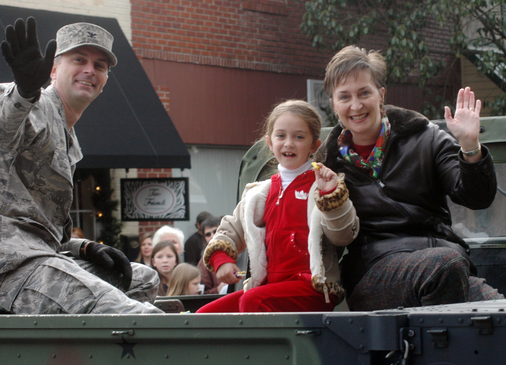 Col. Warren Berry, along with his daughter, Lindsey, and his wife Marie, wave to parade goers from the back of a humvee during Perry's "The Magic of Christmas" parade Dec. 6. U. S. Air Force photo by Sue Sapp