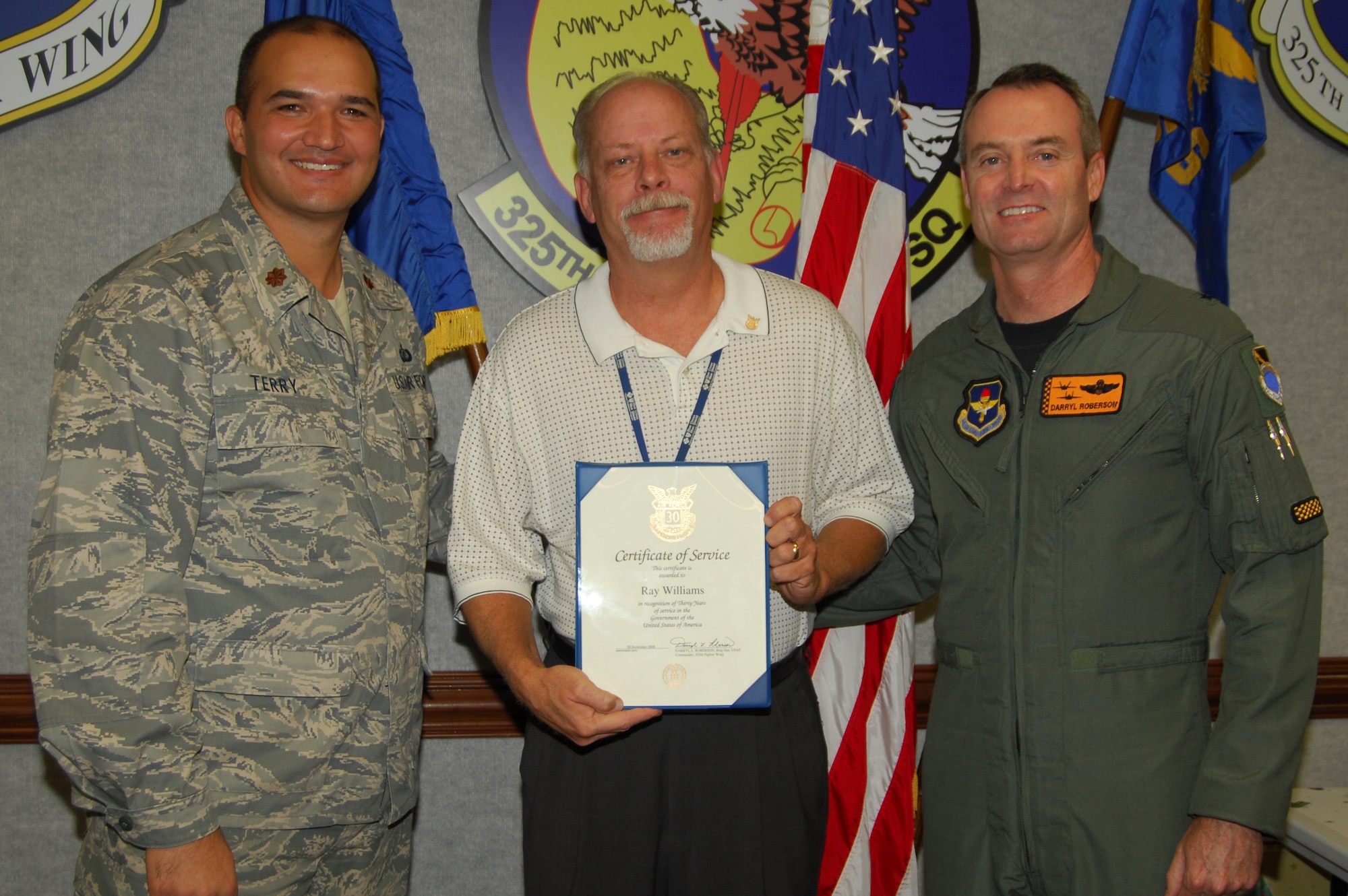 Maj. Jonathan Terry, 325th Contracting Squadron commander and Brig. Gen. Darryl Roberson, 325th Fighter Wing commander, congratulate Ray Williams, 325th CONS construction contracting chief, for his 30 years in civil service with a pin and a certificate.  (U.S. photo by Lisa Norman) 