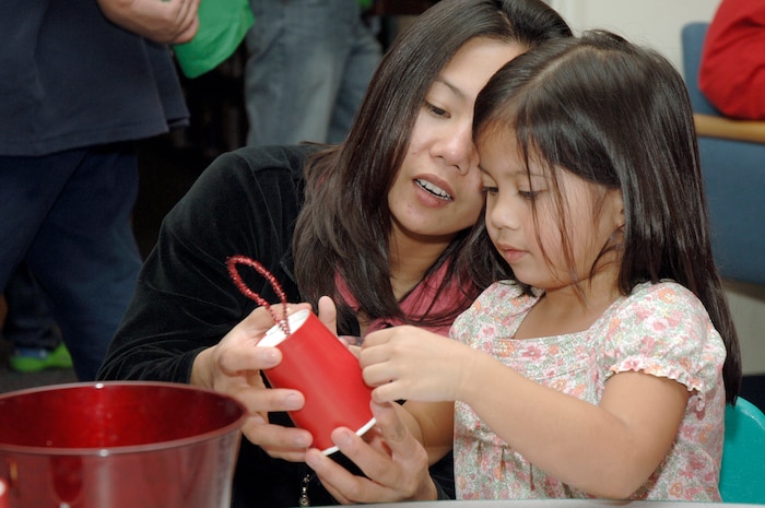 JoAnne Dalope helps her daughter, Julianne, make a tree ornament during the holiday classics party Dec. 9 at the base library. More than 20 children attended the party where they listened to stories, sang carols, made crafts and interacted with Santa. Julianne is also the daughter of Staff Sgt. Marc Dalope who is assigned to the 437th Civil Engineer Squadron. (U.S. Air Force photo/Staff Sgt. Marie Cassetty)