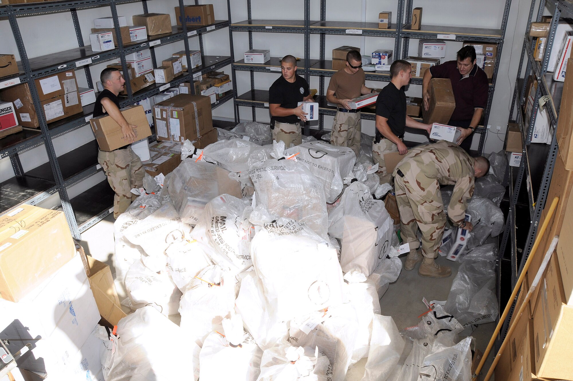 Members of the 380th Expeditionary Civil Engineer Fire and Emergency Services help sort through incoming mail Dec. 8 at an air base in Southwest Asia. The fire department works alongside Alutiiq International Solutions LCC, which is contracted to provide personnel and services for the 380th Air Expeditionary Wing Post Office. They are busy trying to keep the mail coming and going during the busy holiday season. (U.S. Air Force photo/Tech. Sgt. Christopher A. Campbell)
