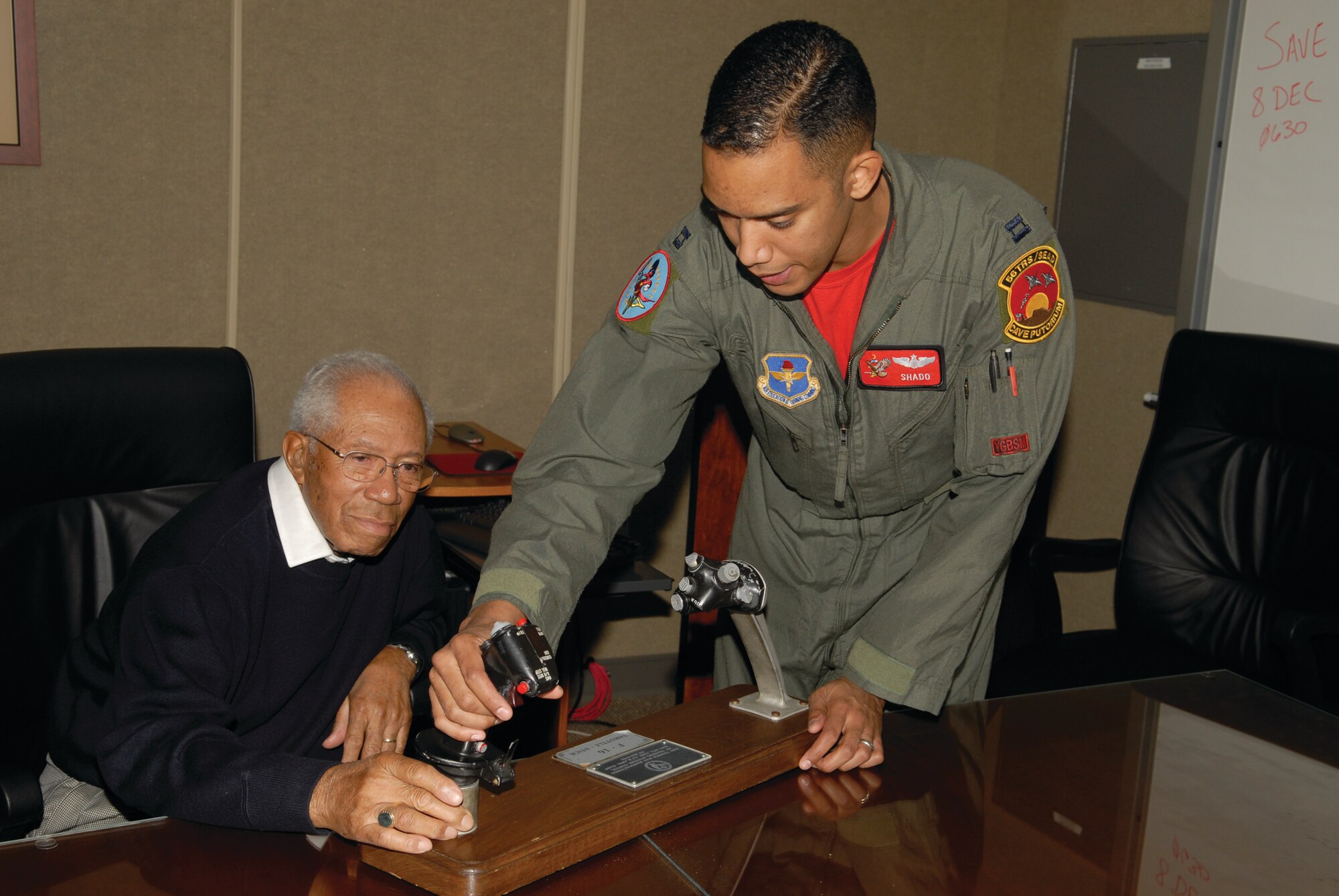 Captain raymond Daniel, 56th Training Squadron instructor pilot, familiarizes Dr. Thurston Gaines, one of the original Tuskegee Airmen, with the flight controls of the F-16 Falcon before entering the flight simulator on Friday, Dec. 5. As part of their base tour, five original members of the Tuskegee Airmen got the chance to "fly" in the F-16 flight simulator.