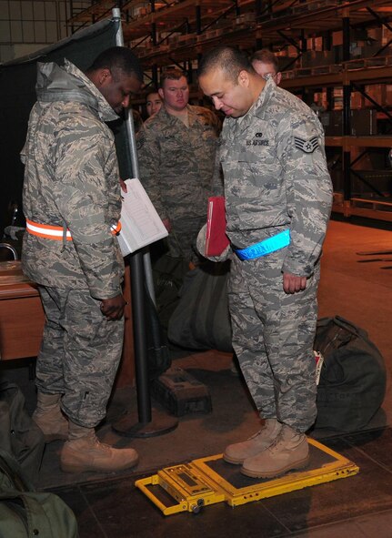 Staff Sgt. Ruben Olivas, 100th Aircraft Maintenance Squadron, takes his turn at being weighed before checking his A, B and C bags at the bag drag exercise in Building 550 Dec. 9, 2008. All personnel and bags have to be weighed so the total weight can be provided to folks on the flightline. Aircraft have a weight limit they have to adhere to before they can take off, so aircrews needs to know what weight they will be carrying. (U.S. Air Force photo by Karen Abeyasekere)