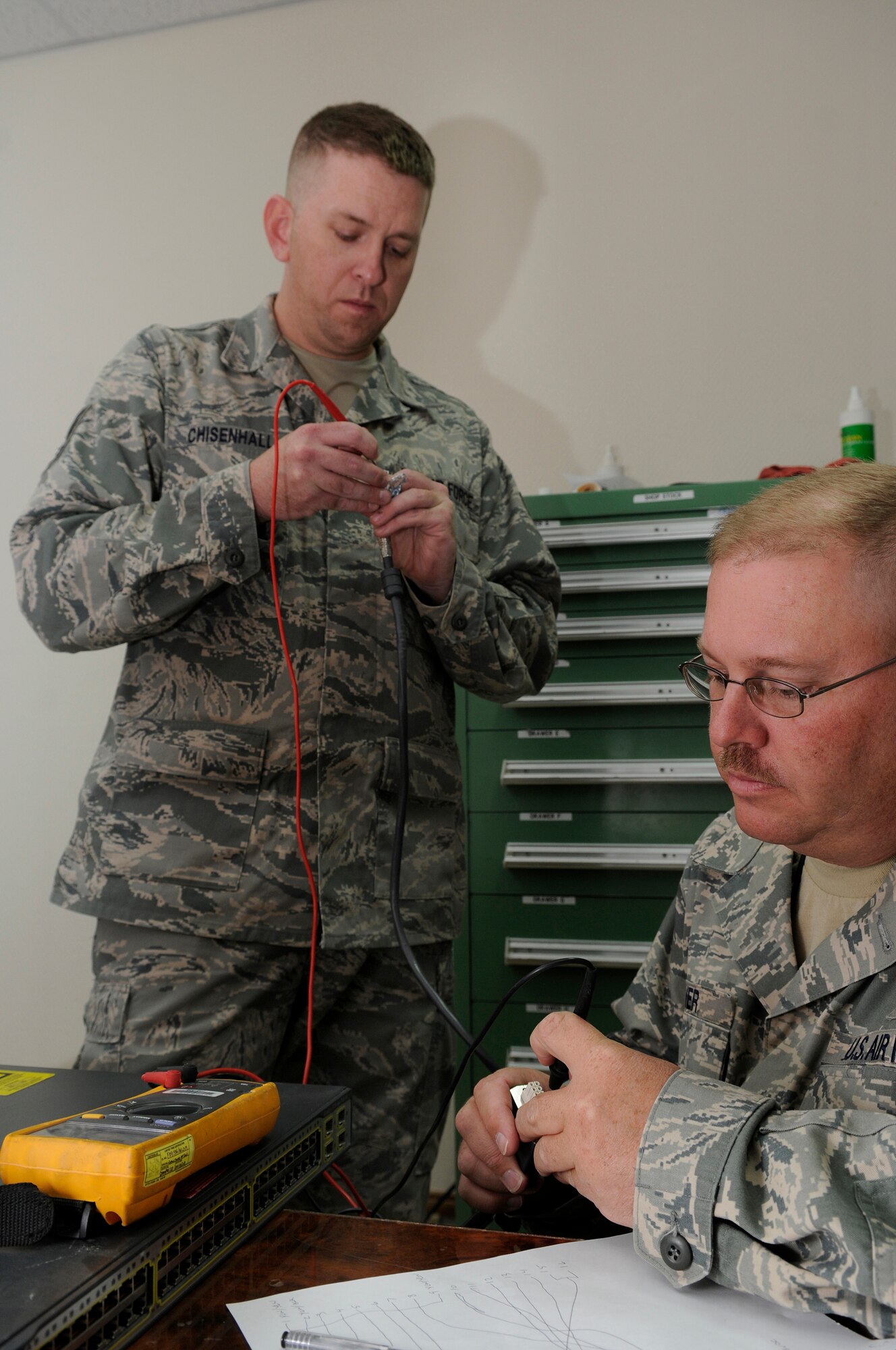 Tech. Sgts. Stephen Chisenhall and Theodore Driver, satellite wideband telemetry and space systems craftsmen assigned to the 379th Expeditionary Communications Squadron, verify a pin-out before engineering a power cord to accept redundant power, Dec. 10, at an undisclosed air base in Southwest Asia.  The redundant power is needed to keep lines of communication open to the farthest areas of the base in the event of power outage.  Sergeant Chisenhall, a native of Raleigh, N.C., is deployed from Royal Air Force Croughton, England.  Sergeant Driver hails from Erie, Pa., and is deployed from Kadena Air Base, Japan.  Both are deployed in support of Operations Iraqi and Enduring Freedom and Joint Task Force-Horn of Africa.  (U.S. Air Force photo by Tech. Sgt. Michael Boquette/Released)
