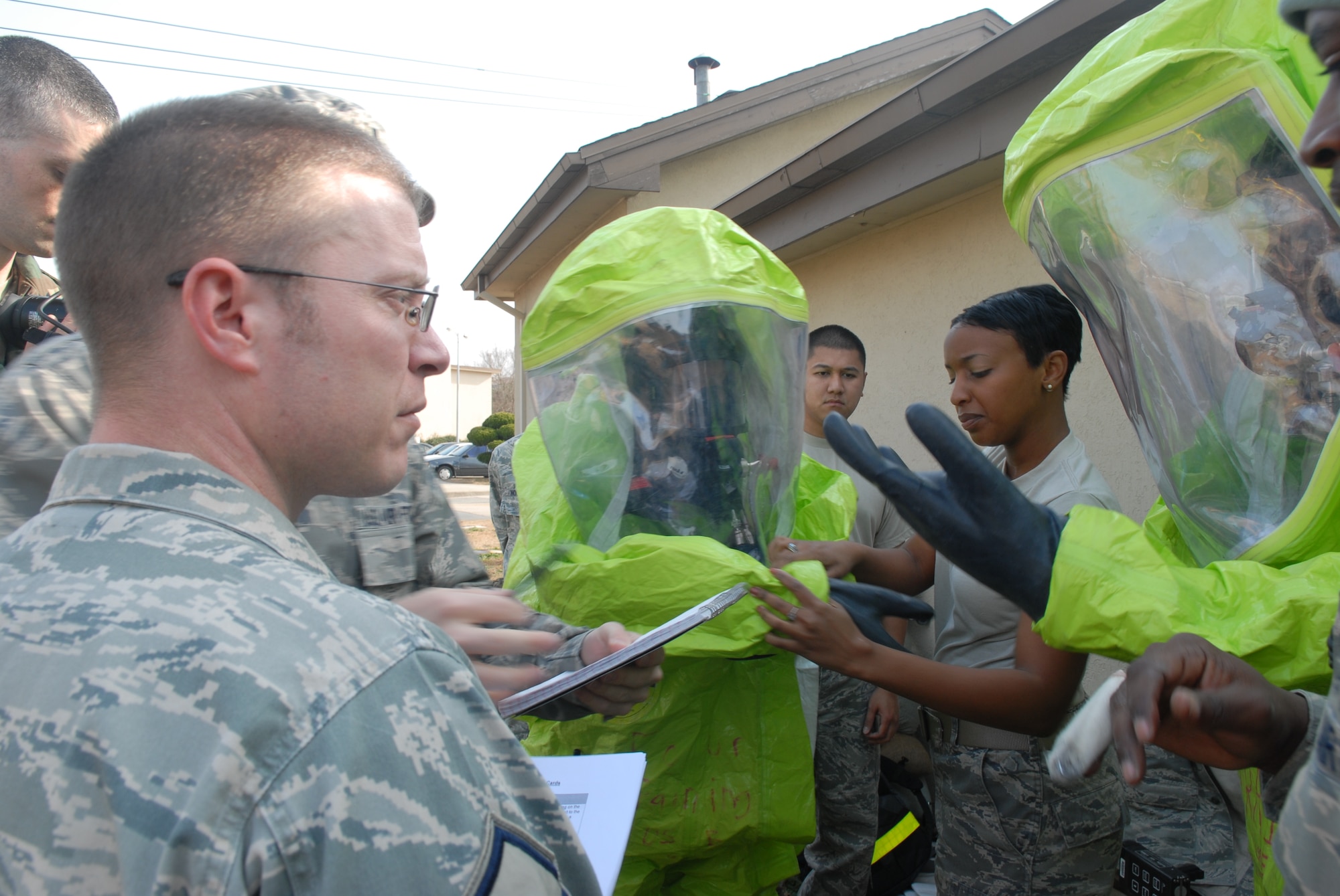 KUNSAN AIR BASE, Republic of Korea – Master Sgt. Dennis Bensel, Exercise Evaluation Team member observes as Senior Airman Tia Strong helps Senior Airman Brandon Kamai, and Tech. Sgt. Paul Johnson, all with the 8th Medical Operations Squadron, don their Self Contained Breathing Apparatus during the All Hazards Response Training here Dec. 9.AHRT is a weeklong training that tested all the base agencies on their response and capabilities during crisis scenarios.(U.S. Air Force photo by: Senior Airman Angela Ruiz)
