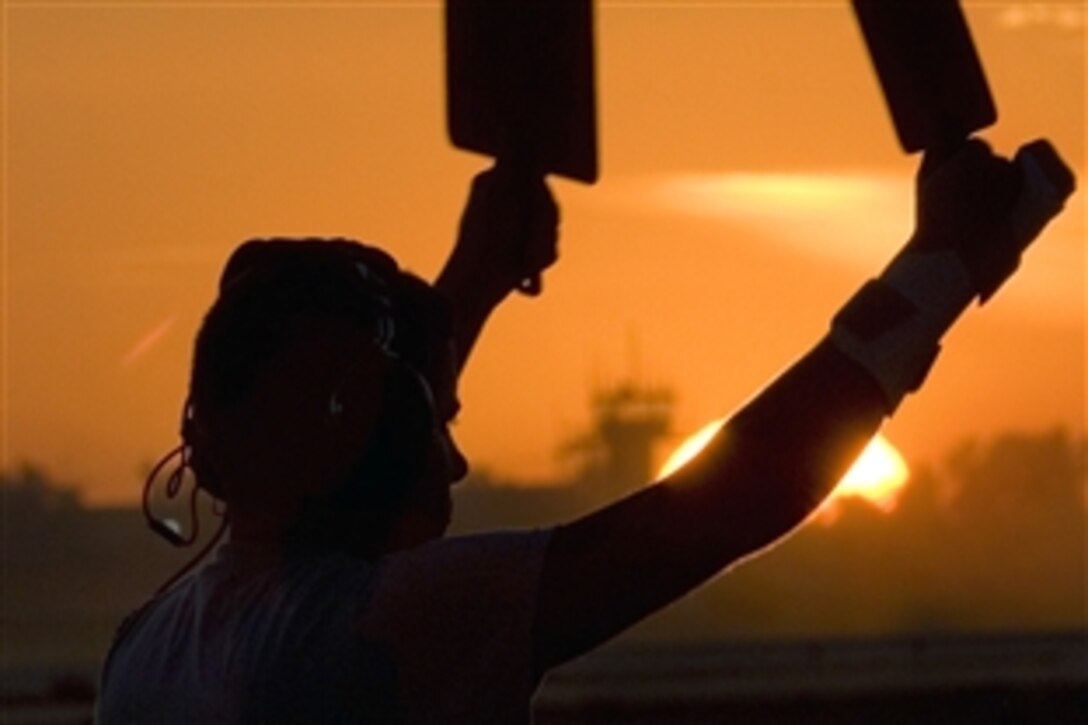 U.S. Airman 1st Class Chadley Williams uses marshaling paddles to direct a C-130 Hercules aircraft onto a taxiway on Joint Base Balad, Iraq, Dec. 6, 2008. Williams is assigned to the 777th Expeditionary Airlift Squadron.