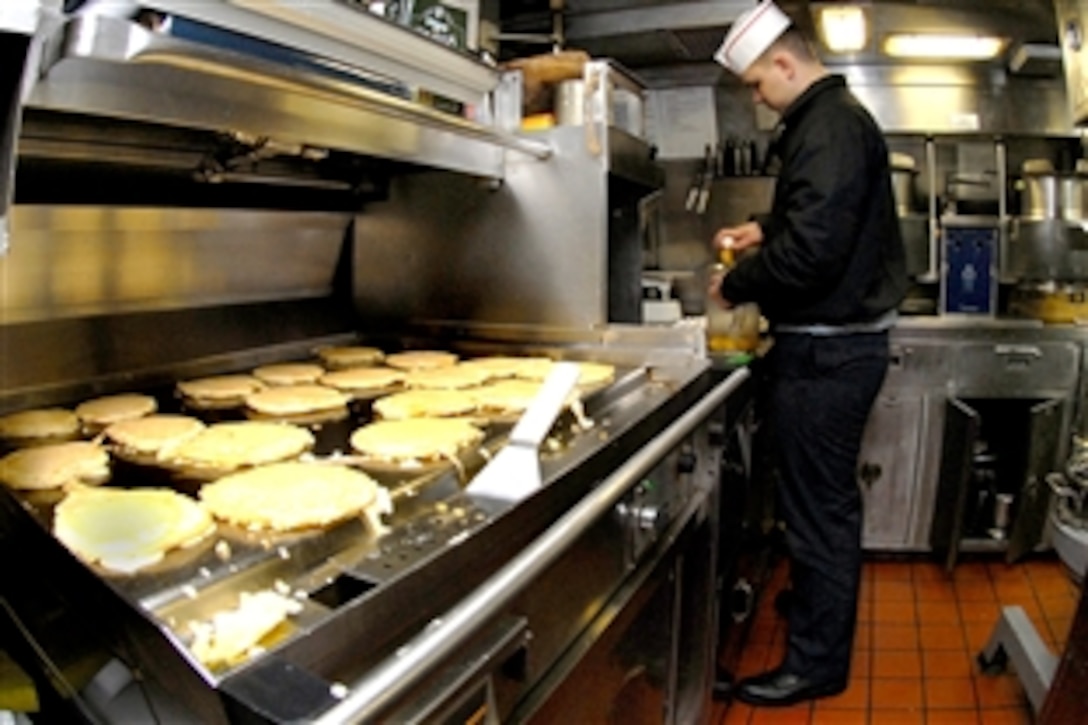 U.S. Navy Seaman Apprentice Henry Kennedy, a culinary specialist, breaks eggs while pancakes cook on the grill aboard the submarine USS Albany, docked in Norfolk, Va., Dec. 10, 2008.