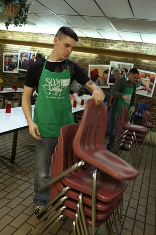 Pfc. Daniel Holder, Guard Company, Marine Barracks Washington, stacks chairs before his group of volunteers sweeps and mops the deck of the So Others Might Eat food kitchen in Washington, Dec. 11. The demand for charity services has increased dramatically since the recession began, and many families are now seeking help from SOME.