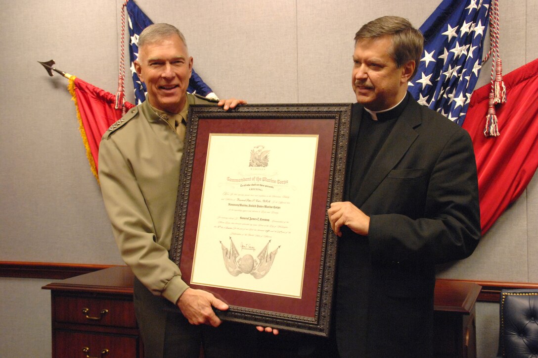 Gen. James T. Conway, commandant of the Marine Corps, presents Father Peter F. Vasko with an Honorary Marine certificate Dec. 12 inside the Pentagon. Vasko has served as the unofficial chaplain for Jerusalem's Marine Security Guard detachment for the past 18 years.::r::::n::