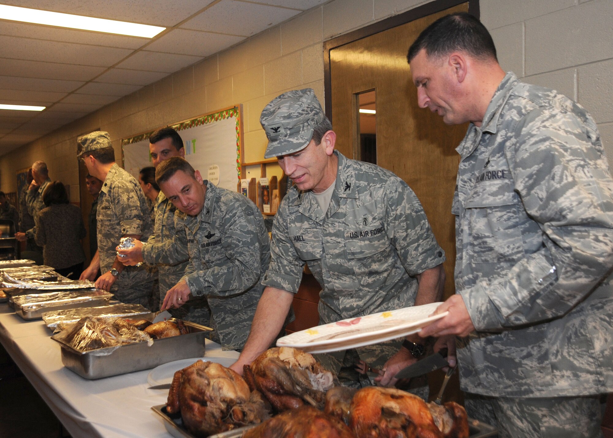 CANNON AIR FORCE BASE, N.M.-- Col. Mark LaRose, (right) 27th Special Operations Maintenance Group commander, Col. Kenneth Hall, 27th Special Operations Medical Group Commander, and Col. Hans Kaspar, 27th Special Operations Wing Vice Commander, serve a holiday dinner at the Single Airmen Christmas Dinner Dec. 11 at the base chapel. Nearly 200 Cannon Airmen participated in the event, during which more than 30 gifts, donated by the local community, were given.  (U.S. Air Force photo by Airman 1st Class Maynelinne De La Cruz)