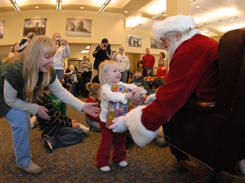 Master Sgt. Susan Schroeder of the 119th Wing assists her daughter as she takes a gift from Santa during the annual 119th Wing Children’s Christmas party at the North Dakota Air National Guard on December 8, 2007.  