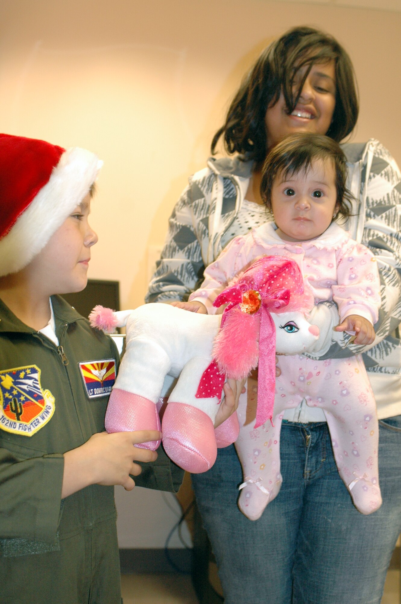 PHOENIX – Honorary 162nd Fighter Wing member Dominic Magne, 7, gives a stuffed animal to a baby at Phoenix Children’s Hospital Dec. 11. The Tucson-based Guard unit held a gift drive in November and December resulting in more than 250 toys, games, books and DVDs. Every child received a gift with extras donated to the hospital for future patients. (Air National Guard photo by Capt. Gabe Johnson)