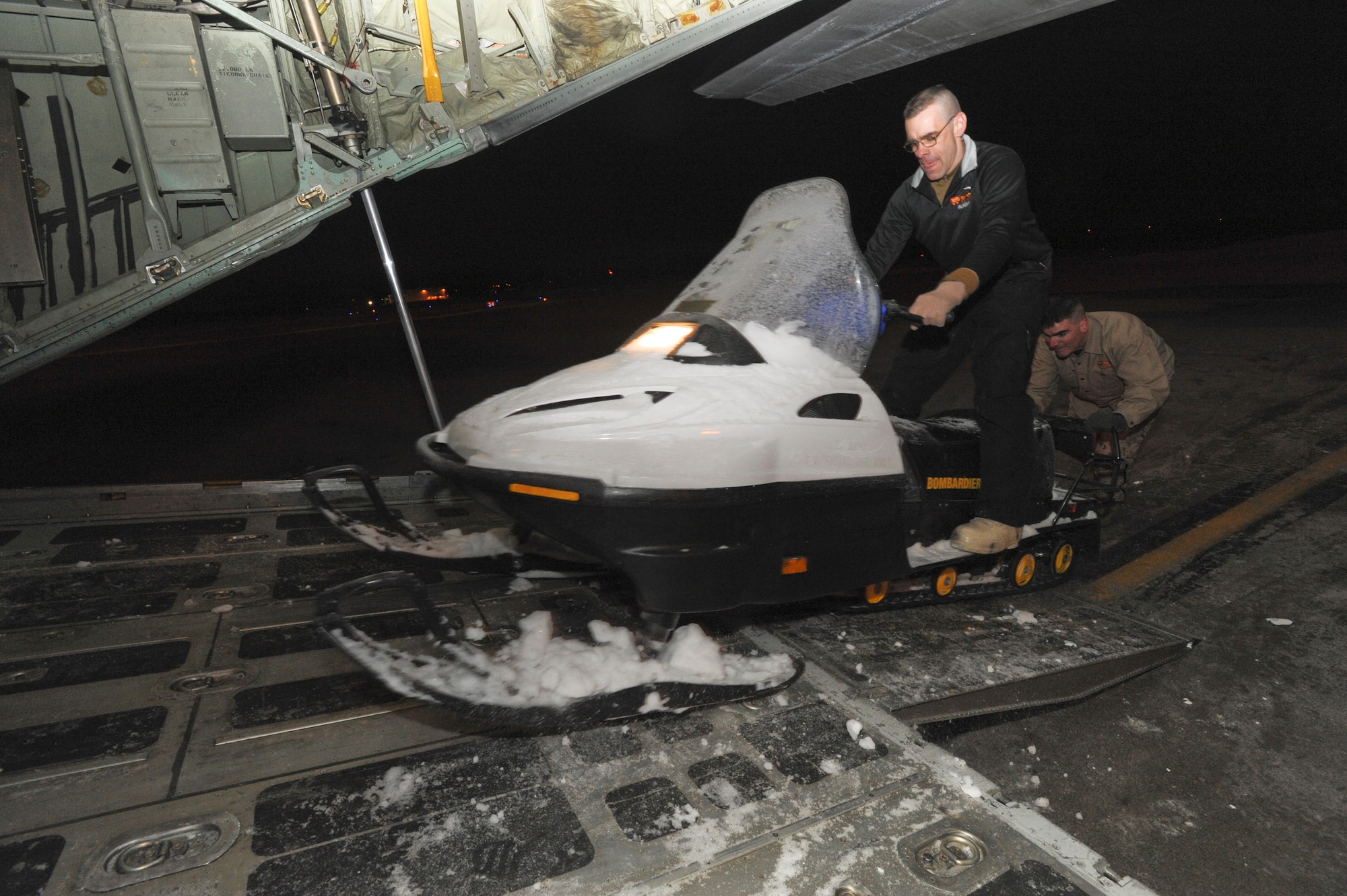 ELMENDORF AIR FORCE BASE, Alaska -- Marine Corps Gunnery Sgt. Bradley Miller, Company D, Anti-Terrorism Battalion 4th Marine Division, load a snowmachine into a Marine C-130 Hercules with the help of Marine Corps Maj. William Allen, Inspector Instructor Staff commander. The Marines are using the snowmachines to deliver toys and supplies to remote villages in Alaska. The toys have been collect by the Marines over the past few months for Toys for Tots and will continued to be delivered throughout the beginning of next year. (U.S. Air Force photo by/Staff Sgt. Joshua Garcia)