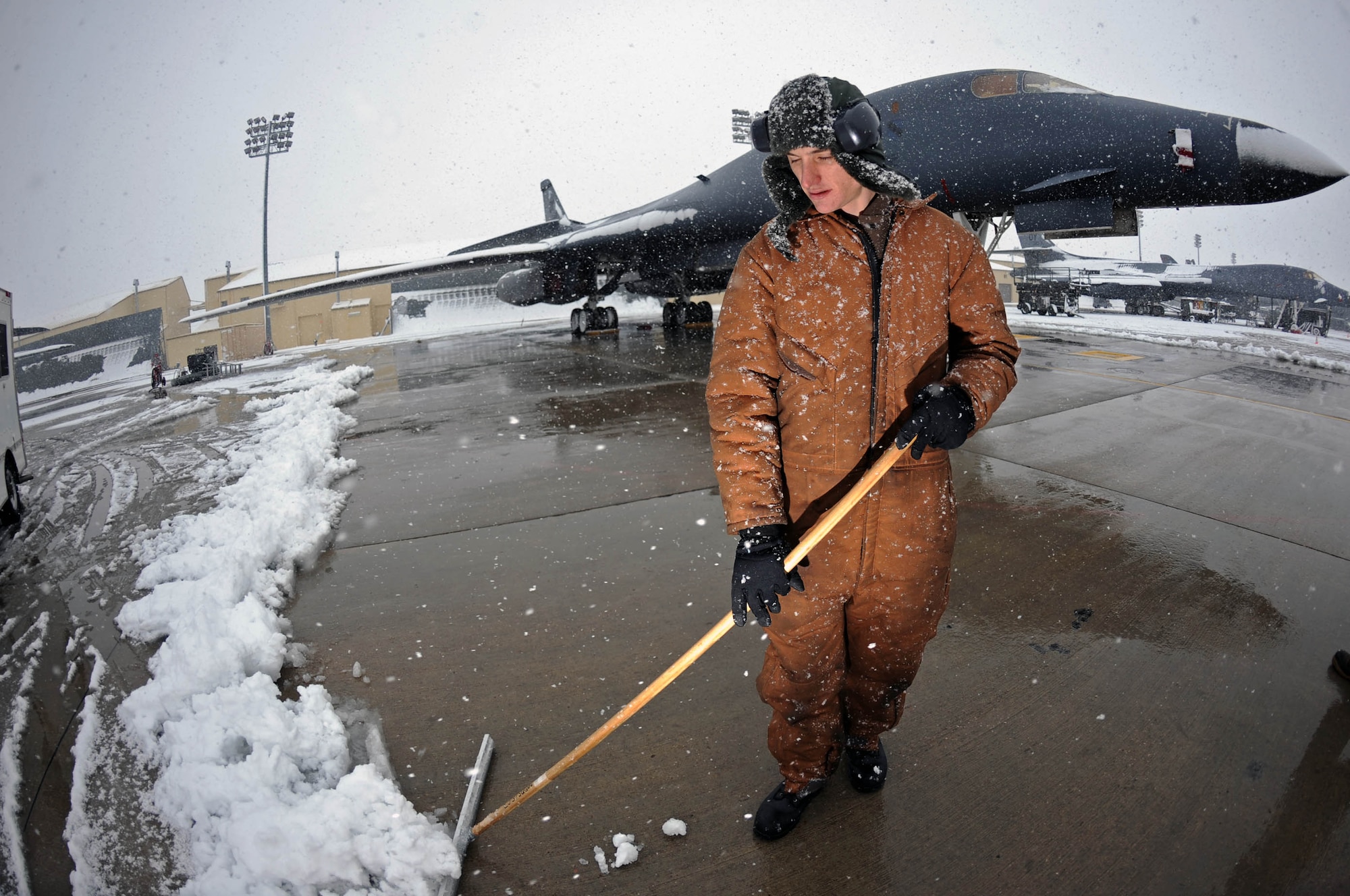 Airman 1st Class Sean Hoke, 37th Bomb Squadron crew chief, sweeps snow away from a B1-B Lancer here, Dec. 11. Removing ice and snow from aircraft and clearing ground surfaces is necessary to maintain operational readiness during winter weather. (US Air Force photo/Airman 1st Class Corey Hook)