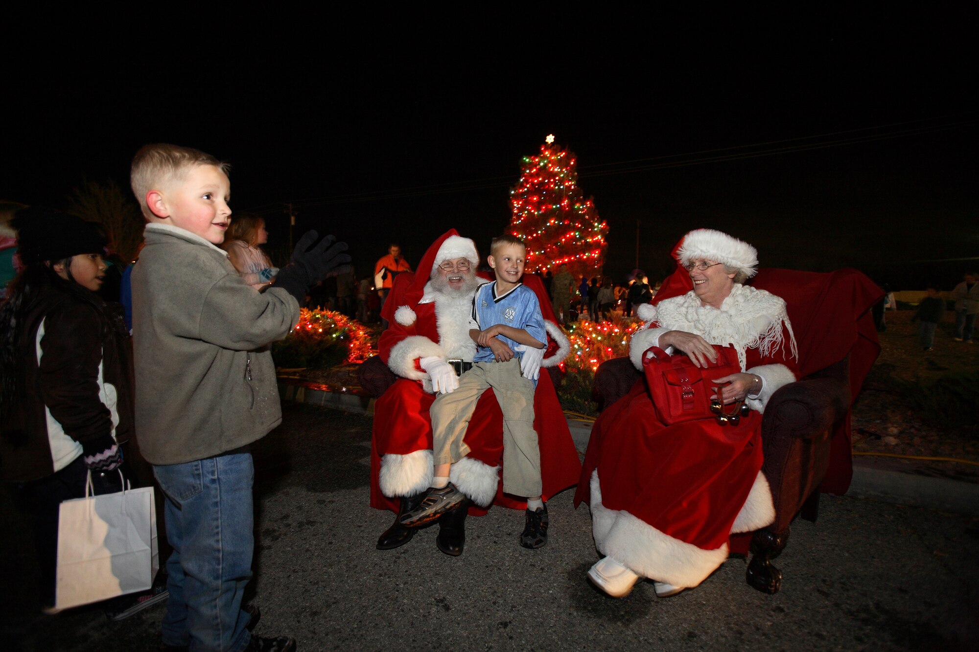 An Edwards child sits on Santa Claus' lap as Mrs. Claus looks on during the Tree-Lighting Ceremony in the Base Exchange parking lot Dec. 10. The tree lighting gives the children on base an opportunity to get free hot chocolate and cookies, listen to Christmas carols, play in the snow and tell Santa what they want for Christmas. (Air Force photo by Jet Fabara)
