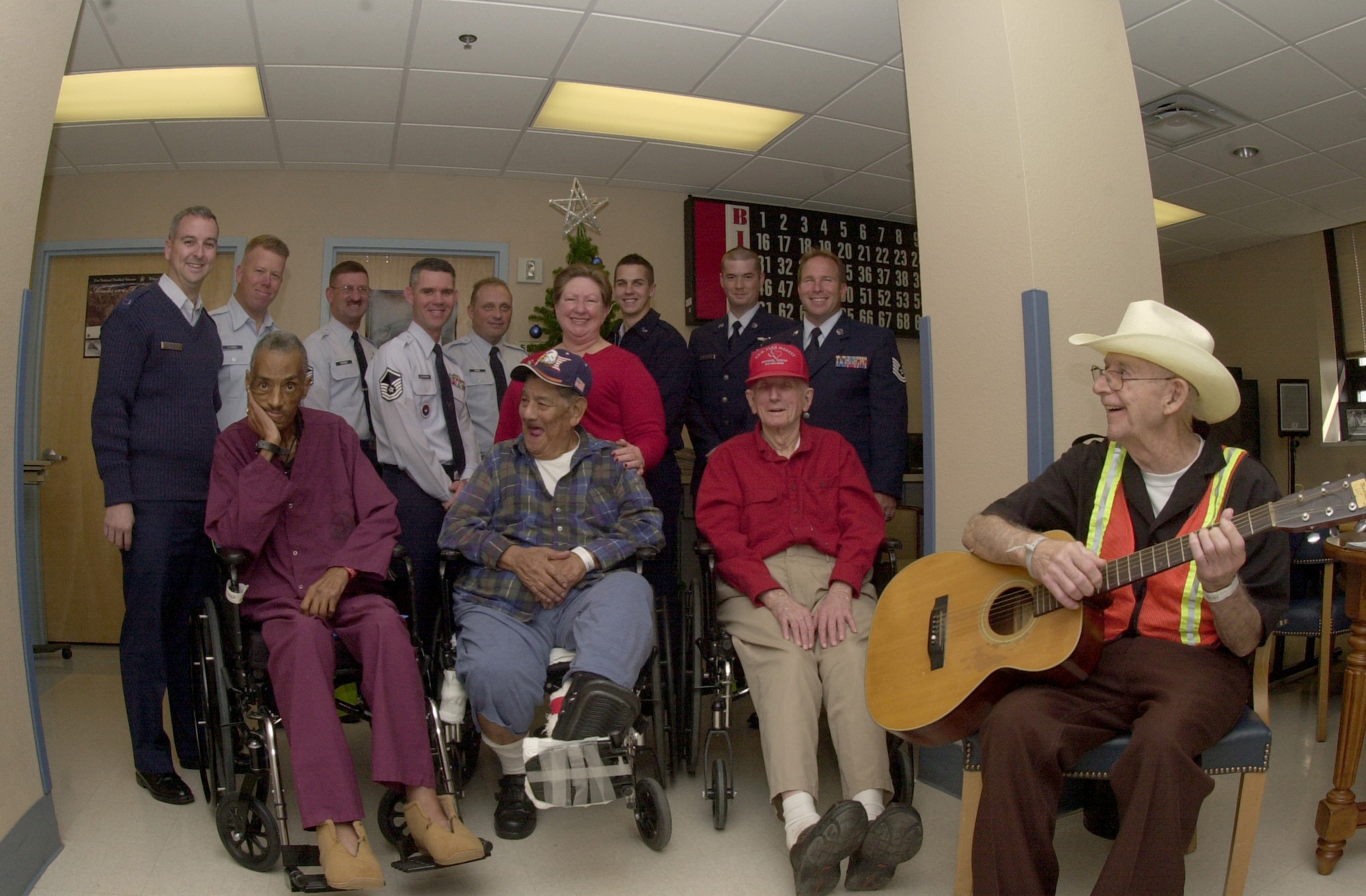 Members from Goodfellow Air Force Base, Texas, pose for a group photo with patients inside the activities room at the Veterans Administration Medical Center. Goodfellow members visited the patients, exchanged stories and entertained the veterans with holiday songs. (U.S. Air Force photo by Senior Airman Luis Loza Gutierrez)