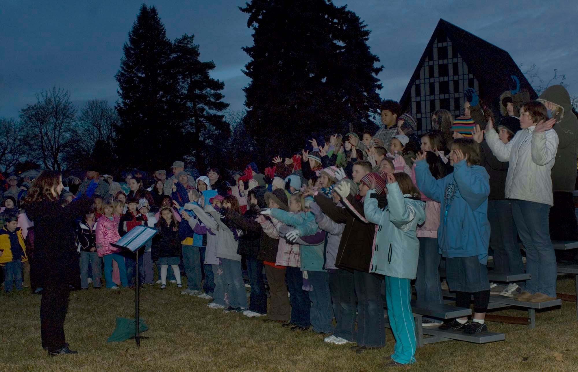 FAIRCHILD AIR FORCE BASE, Wash. – The music director of Michael Anderson Elementary, Rachael Dunn, leads a children’s choir in holiday carols during the annual Christmas-tree lighting ceremony Dec. 3. The children performed for families before lighting the tree. (U.S. Air Force photo / Airman 1st Class Darlene West)