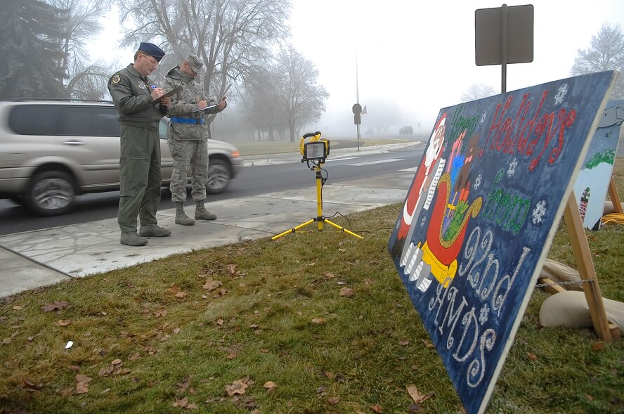 FAIRCHILD AIR FORCE BASE, Wash. – Col. Robert Thomas, 92nd Air Refueling Wing commander, and Chief Master Sgt. David Nordel, 92nd Air Refueling Wing command chief, judge organizational holiday cards as they peruse the sidewalk near the main gate here Dec. 11. Members from squadrons throughout the base spent days preparing the cards that will stand in front of the base Christmas tree throughout the holiday season. Winners of the contest will be announced in Wing Stand Up on the Dec. 17. (U.S. Air Force photo / Senior Airman Joshua K Chapman)