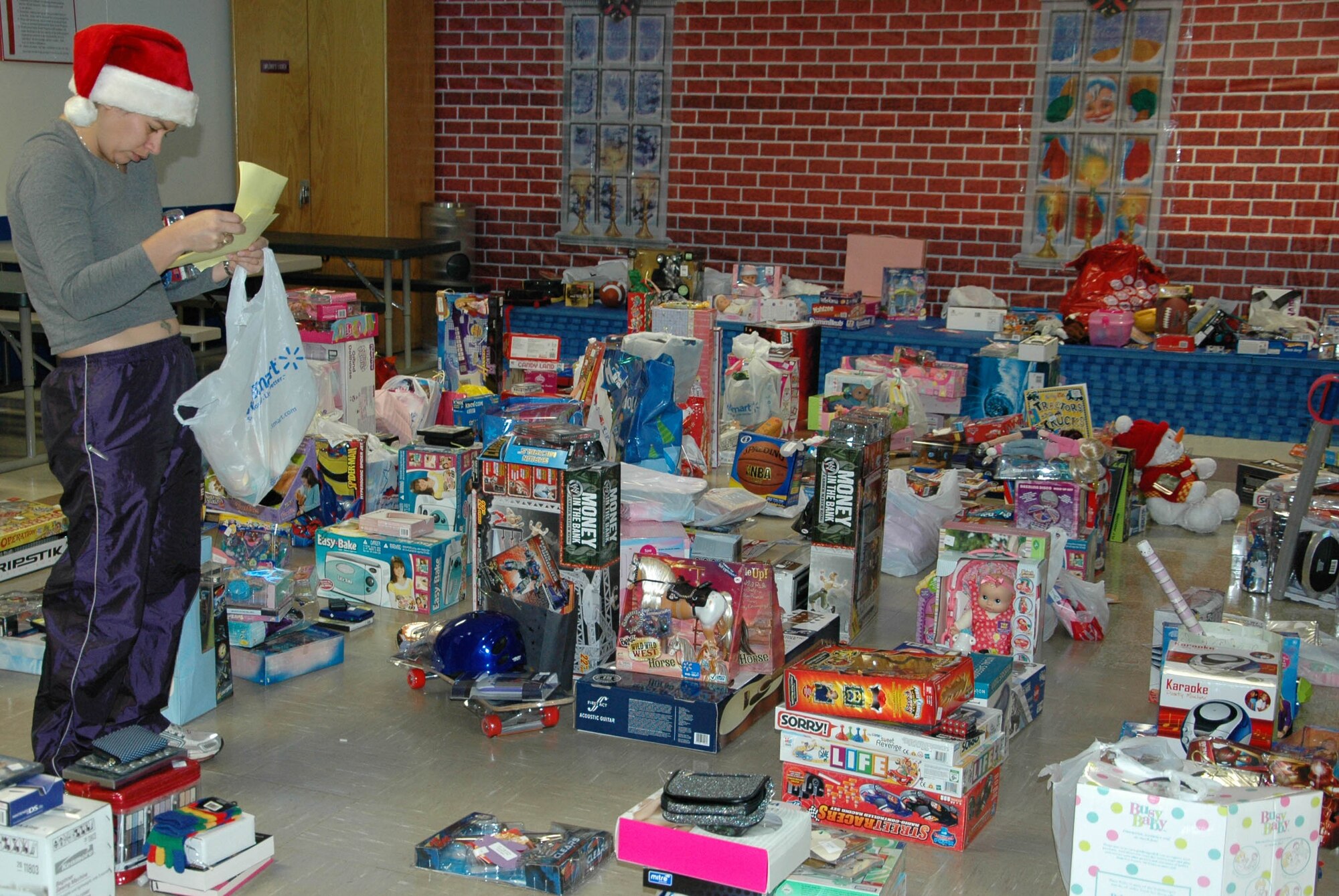 EGLIN AIR FORCE BASE, Fla. -- Capt. Catherine Porcher, 46th Test Wing, checks the wish lists twice before sending the gift piles off to be wrapped for the 28th Annual Give a Child a Christmas event. Children from low-income families and currently in foster care, protective custody or out-of-home situations the opportunity to experience a day filled with gifts and activities including games, lunch and a movie. (U.S. photo/ Staff Sgt. Stacia Zachary)