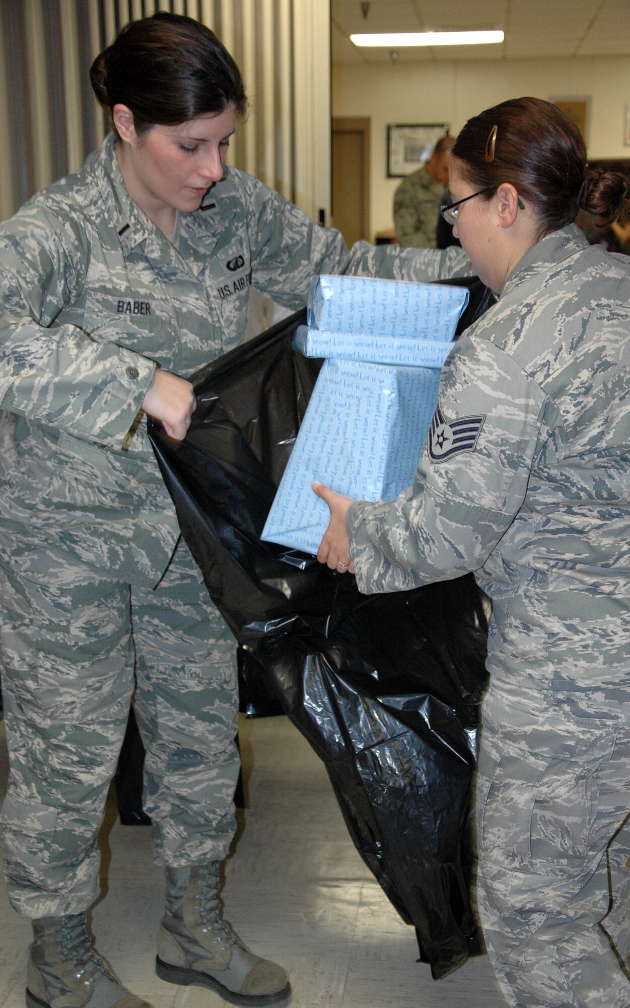 EGLIN AIR FORCE BASE, Fla. -- (From left to right) 1st Lt. Stacy Baber, 28th Test and Evaluation Squadron and the committee chair for the event, and Staff Sgt. LuCeila Ball, Team Eglin Public Affairs, put wrapped presents for the 28th Annual Give a Child a Christmas event into bags. Eachof the 160 children participating in the event will receive a bag. Children from low-income families and currently in foster care, protective custody or out-of-home situations the opportunity to experience a day filled with gifts and activities including games, lunch and a movie. (U.S. photo/ Staff Sgt. Stacia Zachary)