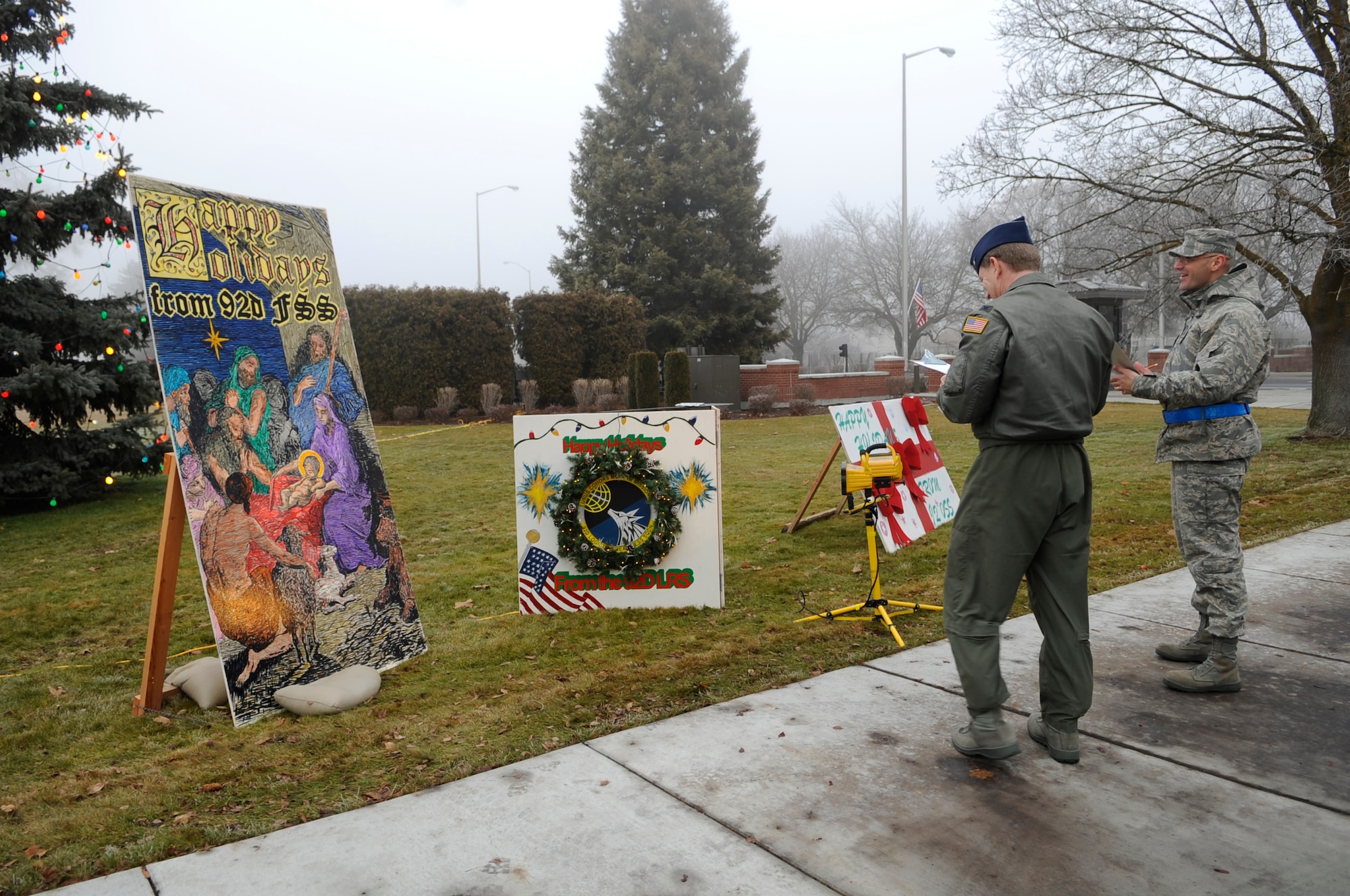FAIRCHILD AIR FORCE BASE, Wash. – Col. Robert Thomas, 92nd Air Refueling Wing commander, and Chief Master Sgt. David Nordel, 92nd Air Refueling Wing command chief, judge organizational holiday cards as they peruse the sidewalk near the main gate here Dec. 11. Members from squadrons throughout the base spent days preparing the cards that will stand in front of the base Christmas tree throughout the holiday season. Winners of the contest will be announced in Wing Stand Up on the Dec. 17. (U.S. Air Force photo / Senior Airman Joshua K Chapman)