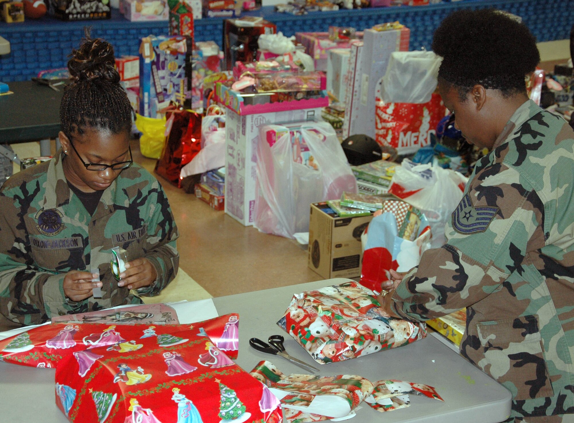 EGLIN AIR FORCE BASE, Fla. -- (From left to right) Airman Ashley Dixon-Jackson and Tech. Sgt. Mardina Hardy, 96th Logistics Readiness Squadron, wrap presents for the 28th Annual Give a Child a Christmas event. Children from low-income families and currently in foster care, protective custody or out-of-home situations the opportunity to experience a day filled with gifts and activities including games, lunch and a movie. (U.S. photo/ Staff Sgt. Stacia Zachary)