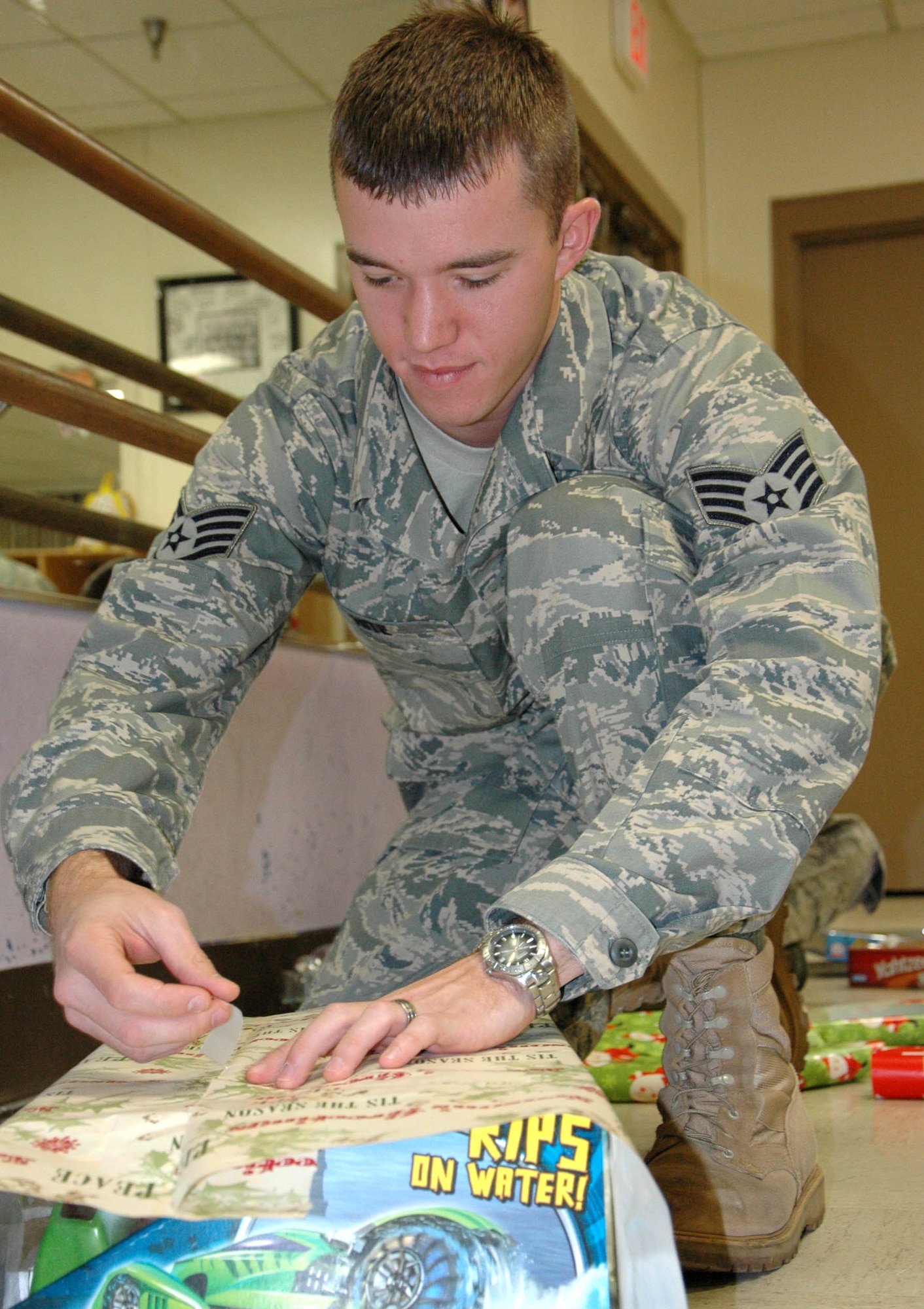 Staff Sgt. Joshua Hite, 96th Logistics Readiness Squadron, wraps a present for the 28th Annual Give a Child a Christmas event. Children from low-income families and currently in foster care, protective custody or out-of-home situations the opportunity to experience a day filled with gifts and activities including games, lunch and a movie. (U.S. photo/ Staff Sgt. Stacia Zachary)