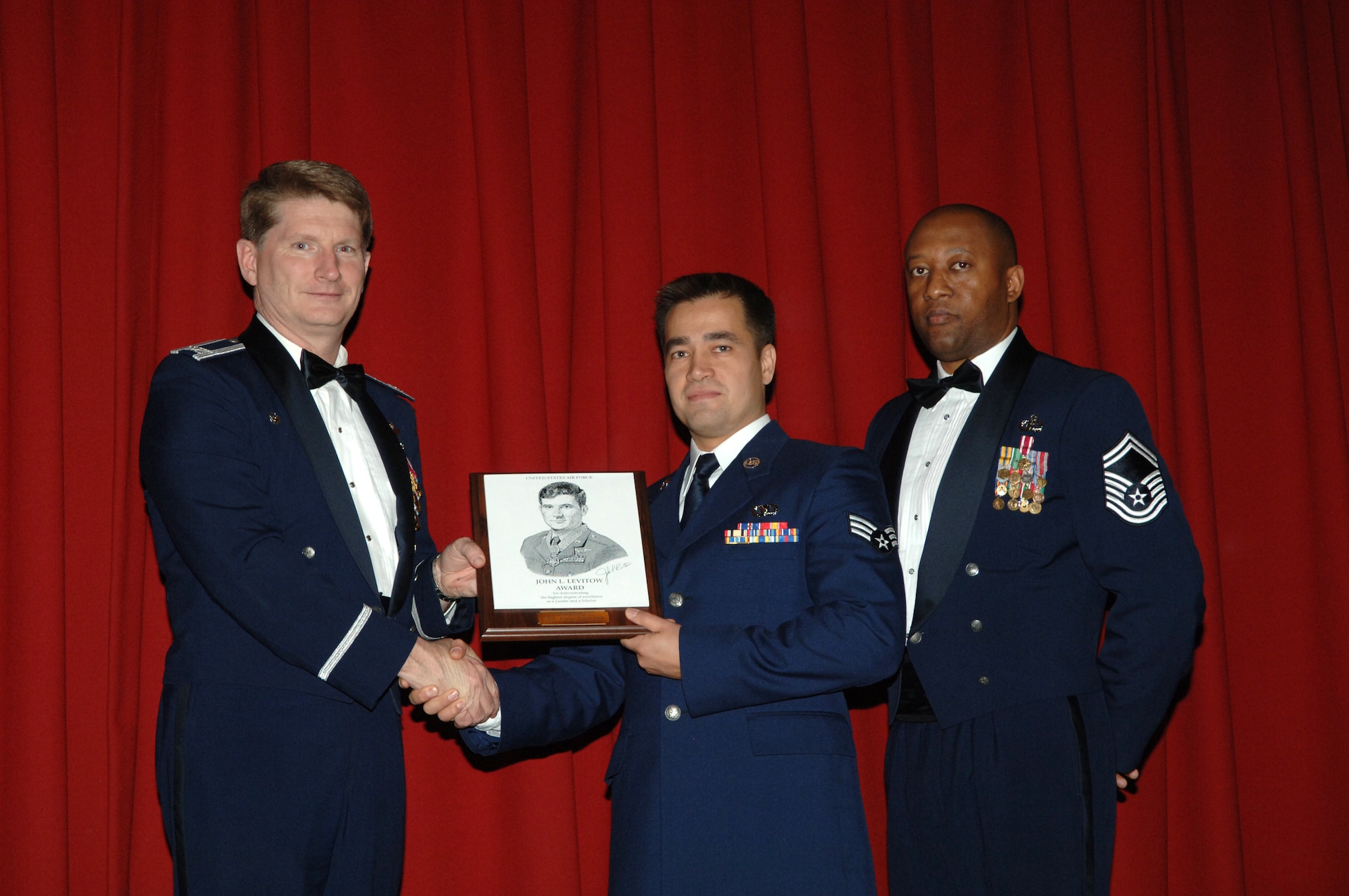 FAIRCHILD AIR FORCE BASE, Wash. – The 92nd Air Refueling Wing Commander Col. Robert Thomas, and Senior Master Sgt. Wesley Mathias, 92nd Operation Support Squadron, present Senior Airman Tony Fancher, 22nd Training Squadron, survival, evasion, resistance and escape specialist, with the John Levitow Award, during the Airman Leadership School graduation Dec. 4. The prestigious award sponsored by the Air Force Sergeants Association is the highest professional military education award bestowed in enlisted PME courses indicating excellence in academics, leadership and peer standing. (U.S. Air Force photo / Senior Airman Jocelyn A. Ford)

