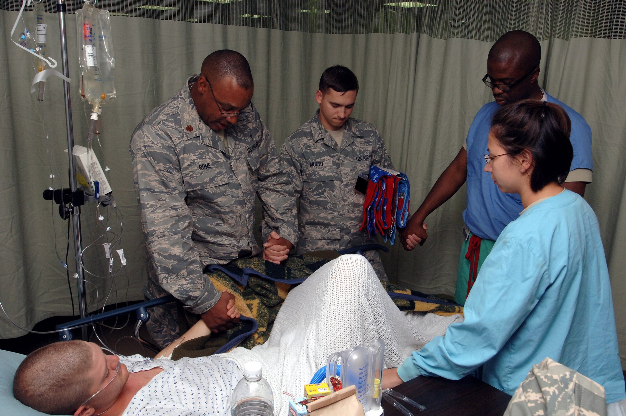 Chaplin (Maj.) Wendell Rome, Staff Sgt. Terry Mueth, Capt. Lawrence Onyejekwe and Capt. Anna Mann pray with Airman 1st Class Wyndal Boothe in the Air Force Theater Hospital Nov. 25 at Joint Base Balad, Iraq. Airman Boothe, a force protection augmentee with the 332nd Expeditionary Security Forces Squadron, received treatment for pneumonia. He is deployed from Charleston Air Force Base, S.C., where he is an aerospace maintenance apprentice. His hometown is Lubbock, Texas. (U.S. Air Force photo/Tech. Sgt. Erik Gudmundson) 
