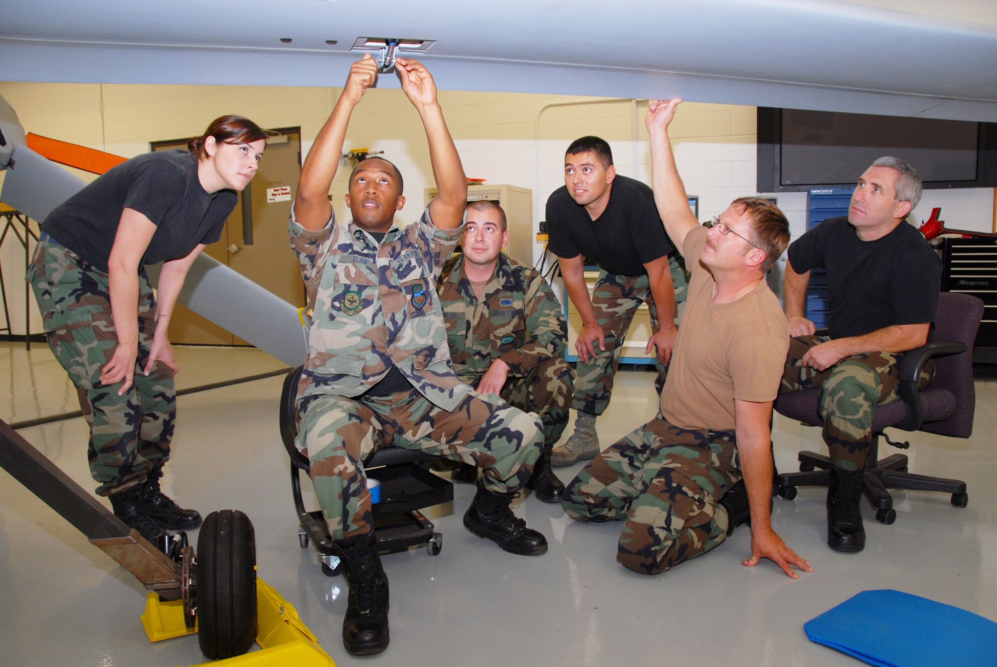 (Left to right) Tech. Sgt. Rebecca Hatfield gives Staff Sgt. Aaron Elam, Senior Airmen Leonard Enciso and Manuel Holguin, Tech. Sgts. Travis Little and Mark Brandt hands-on instruction on the Predator. (U.S. Air Force photos by Staff Sgt. Diane Ducat)