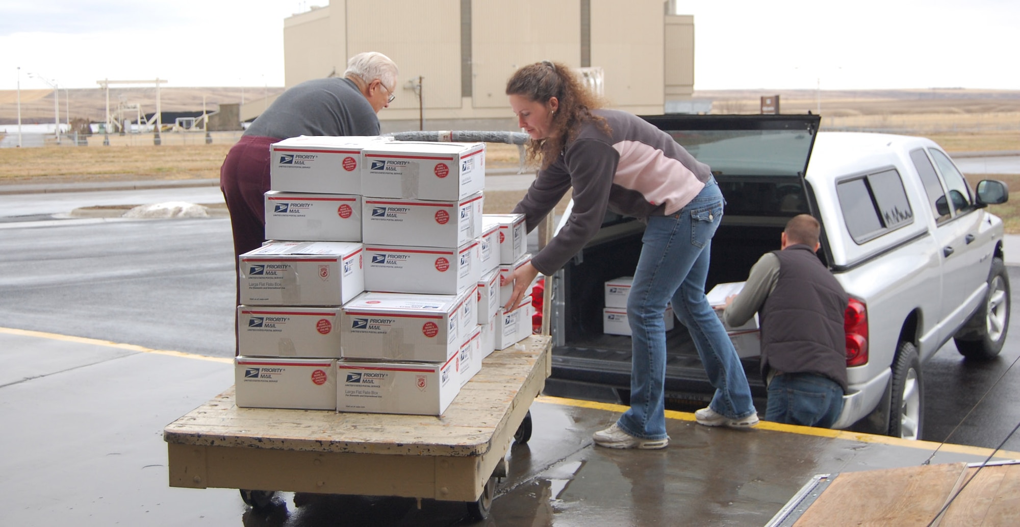 Steve Kubick, retiree, and Tech. Sgt. Tonya Shiffert, 341st Logistics Readiness Squadron, help load the first batch of packed boxes into a truck for transport to the post office Dec. 6. Volunteers packed 200 boxes to be shipped to deployed servicemembers from Montana. (U.S. Air Force photo/Valerie Mullett)